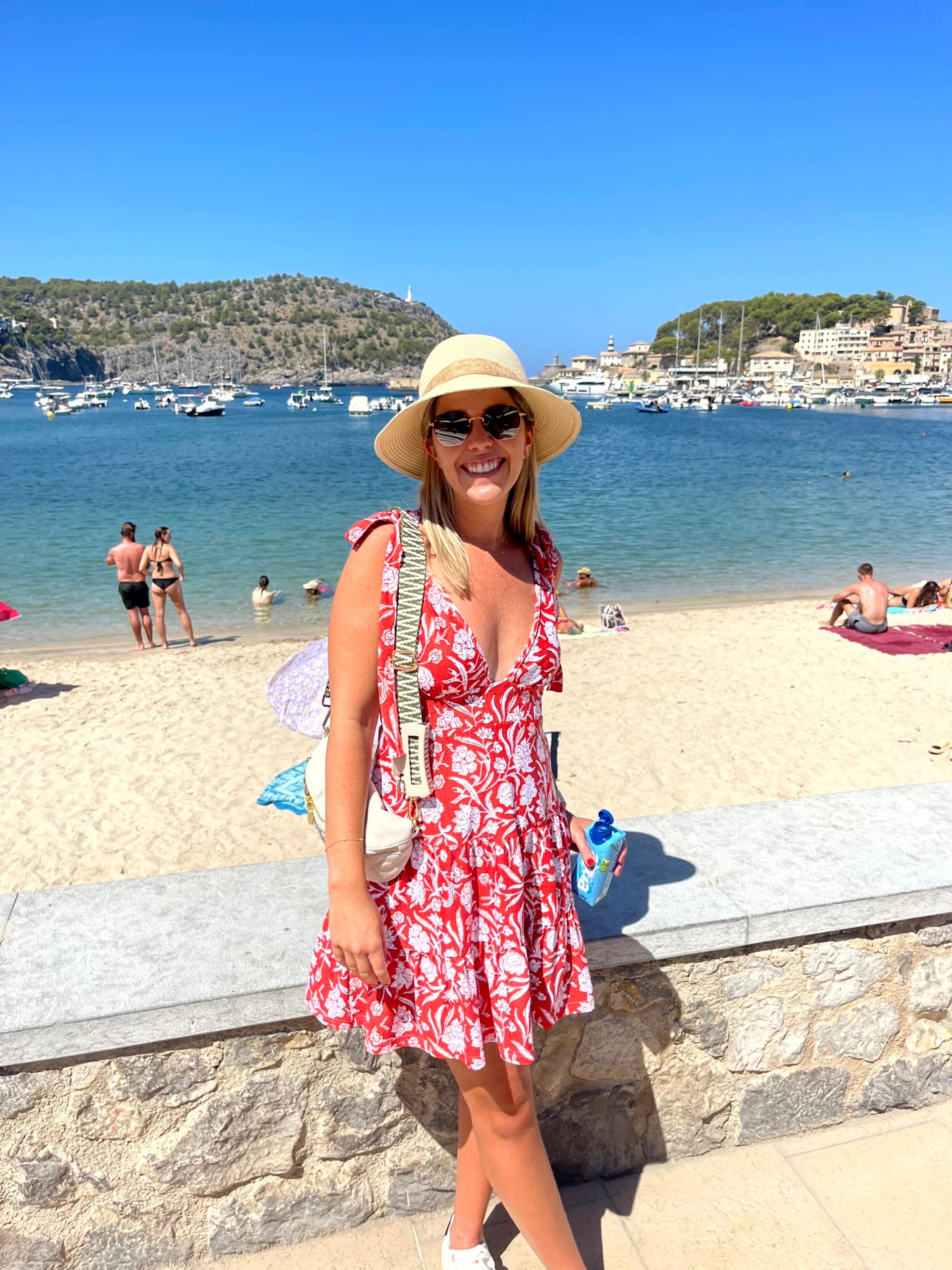 The image portrays a person in a red dress and hat, enjoying a sunny beach day, with their face with a hat.