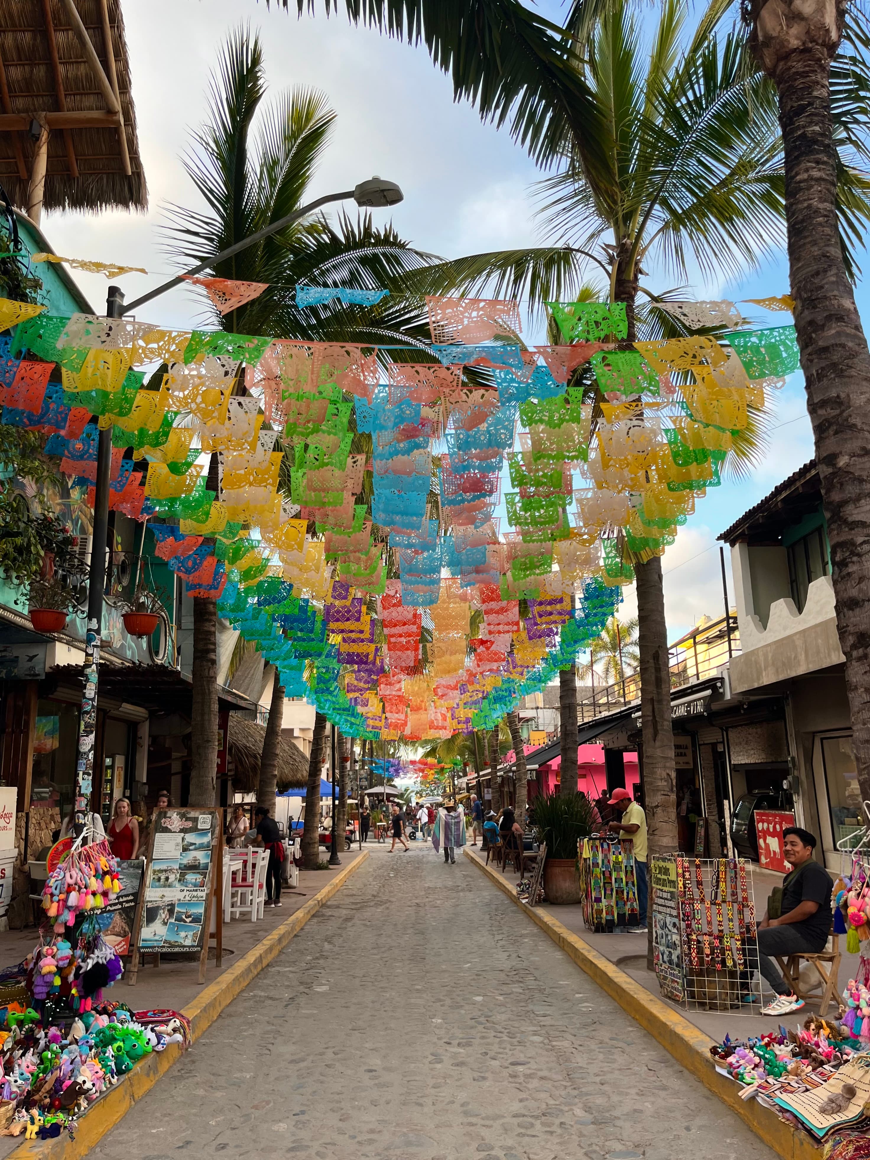Colorful flags hanging above a town street during the daytime