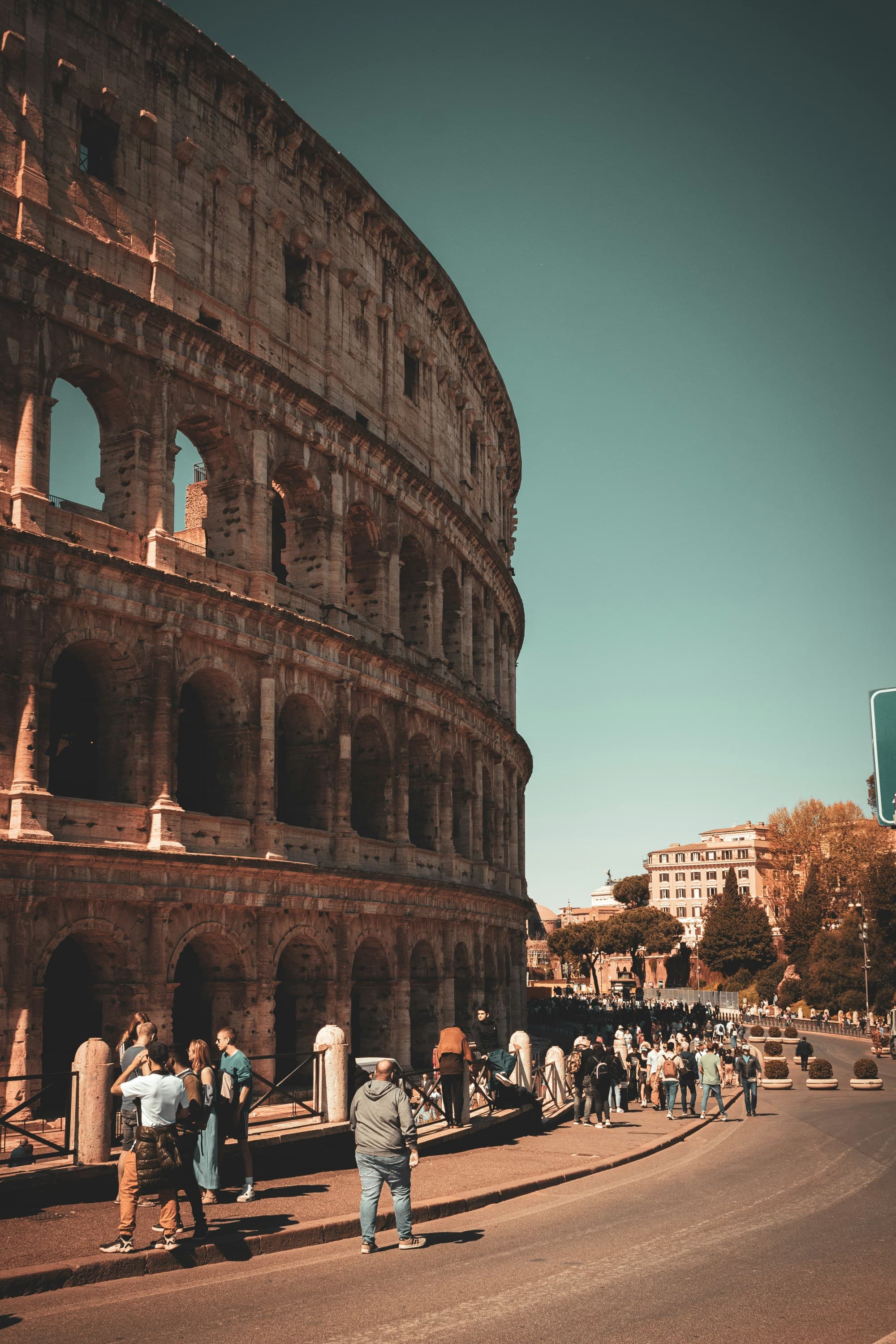 People walking and standing near the Colosseum.