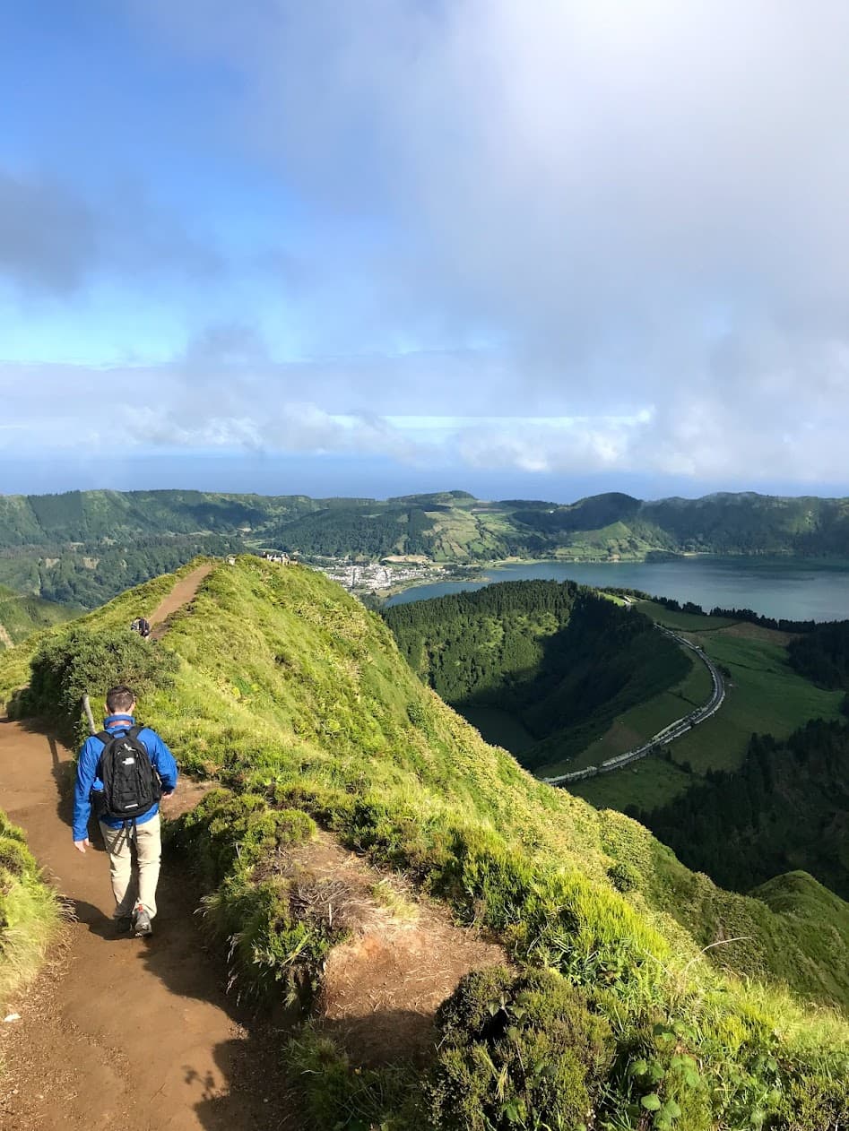 Hiking on a ridge with a large crater lake to the right of the trail below.