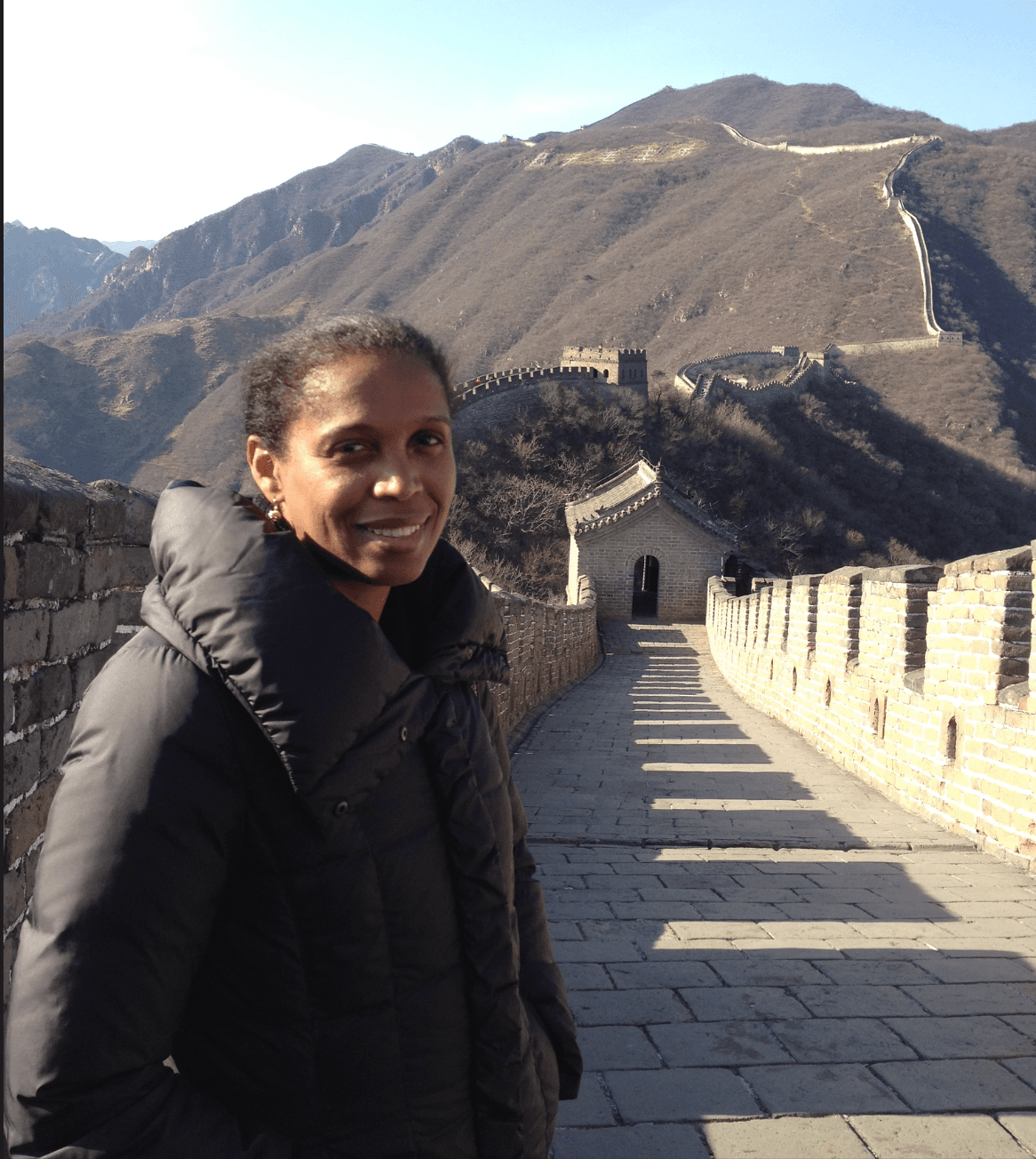 A woman in front of a long wall.