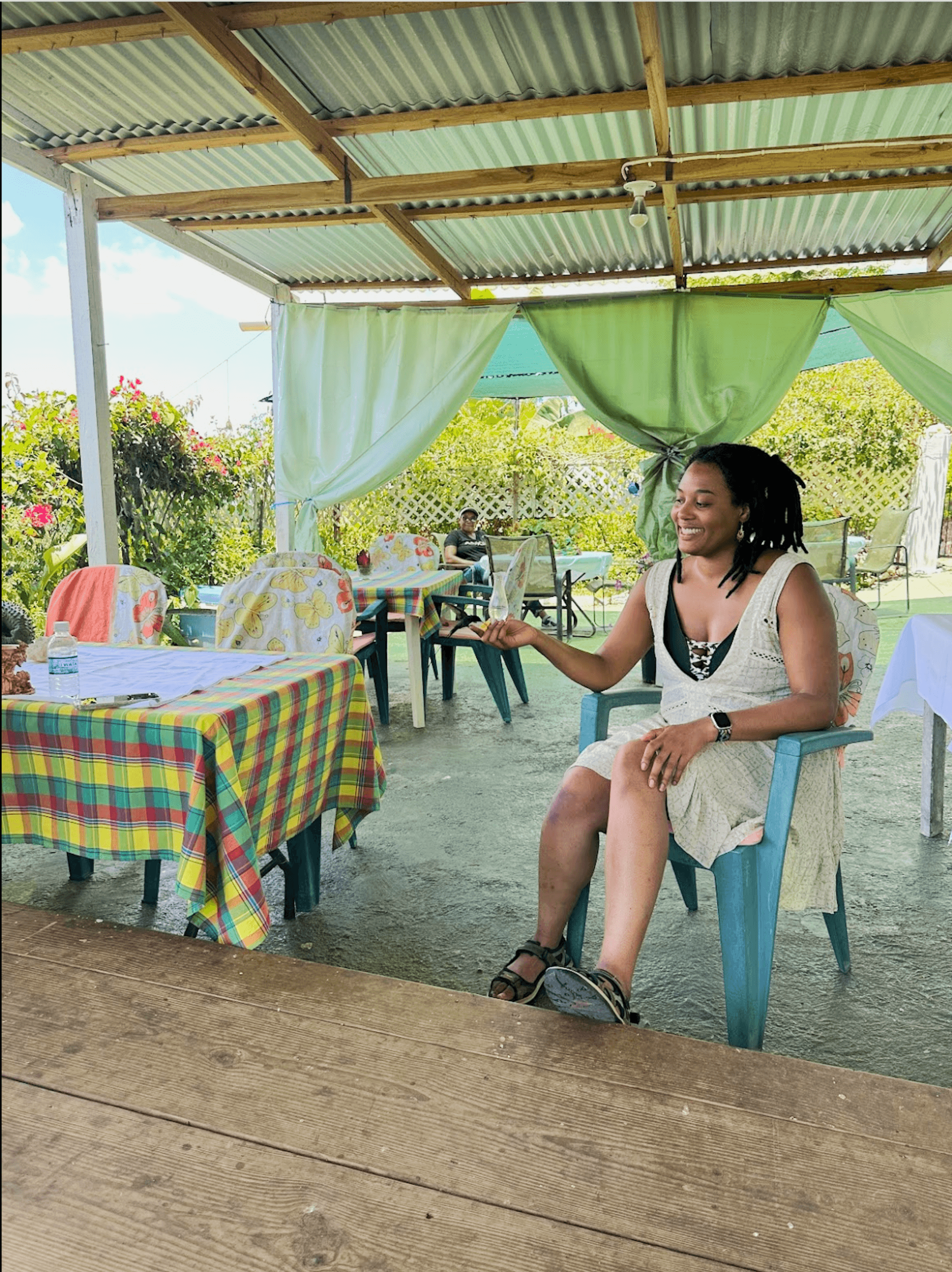 A colorful outdoor dining area with checkered tablecloths and a person seated at one of the tables.