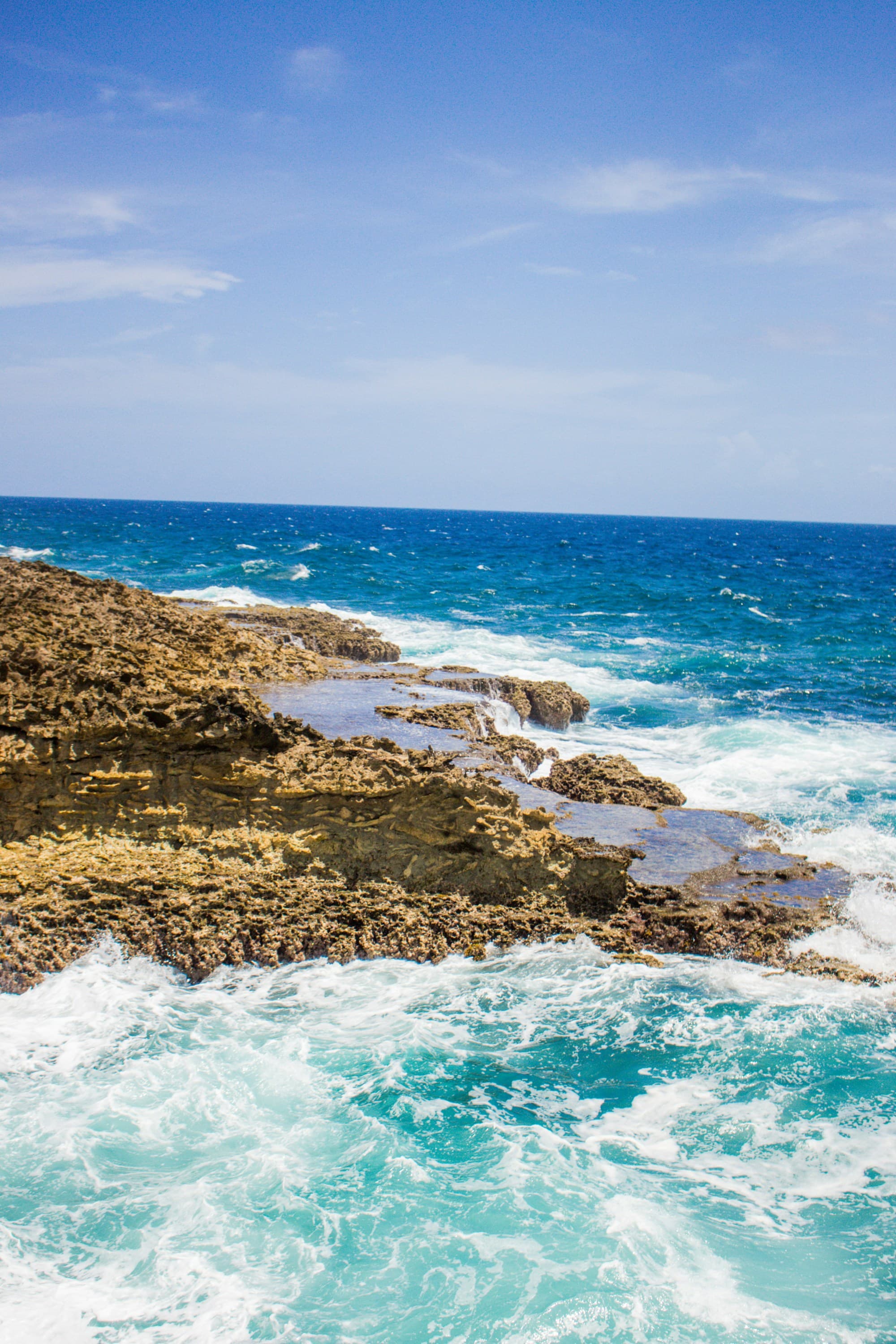 Blue waves crashing against a rock in the ocean during the daytime