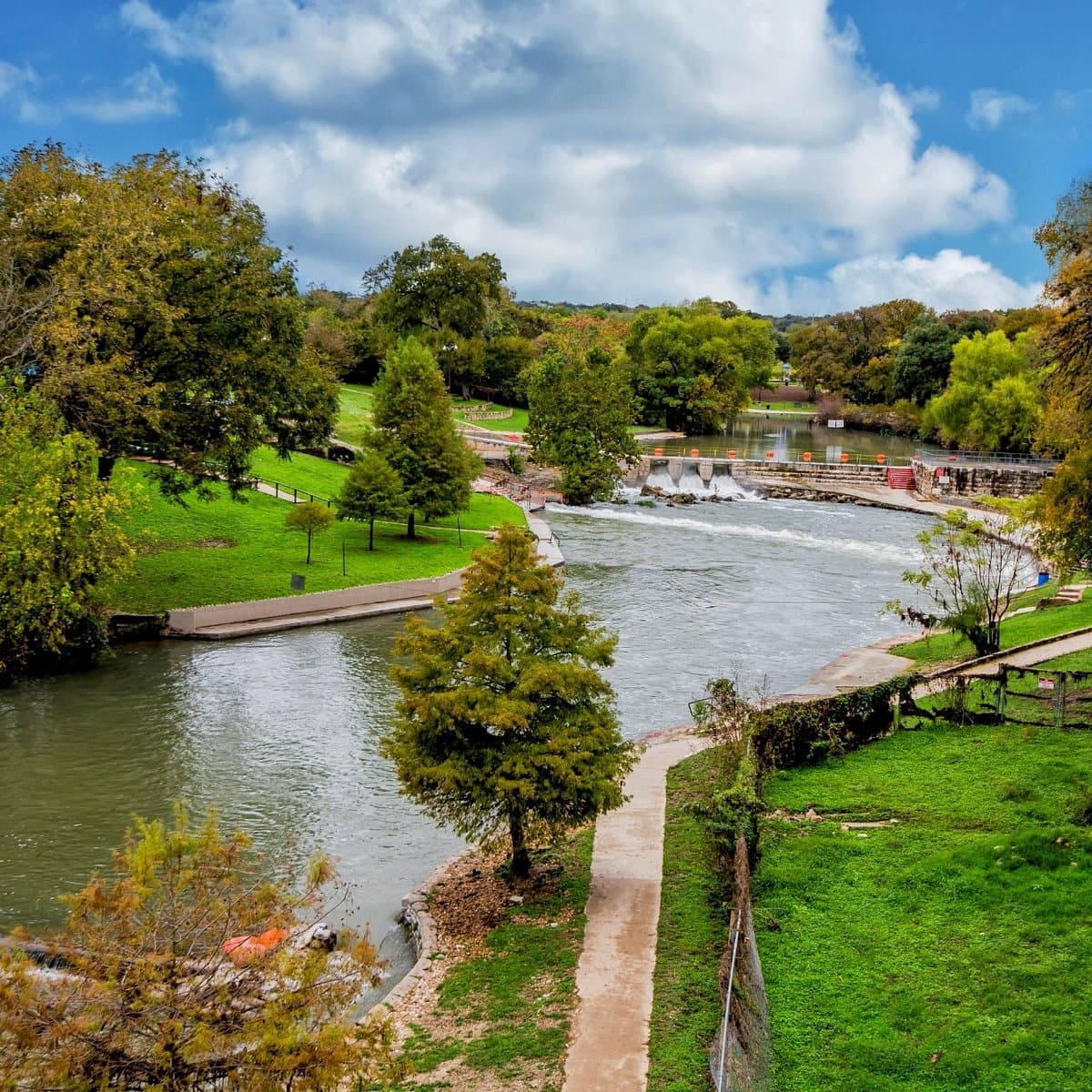 A view of a local park with a river running through it on a sunny day.