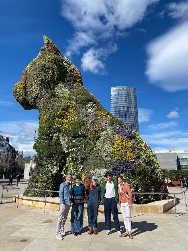 People posing in front of a flower statue of a cat.