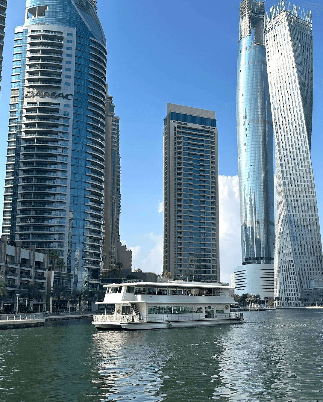 Boat and tall buildings at Dubai Marina on a sunny day.