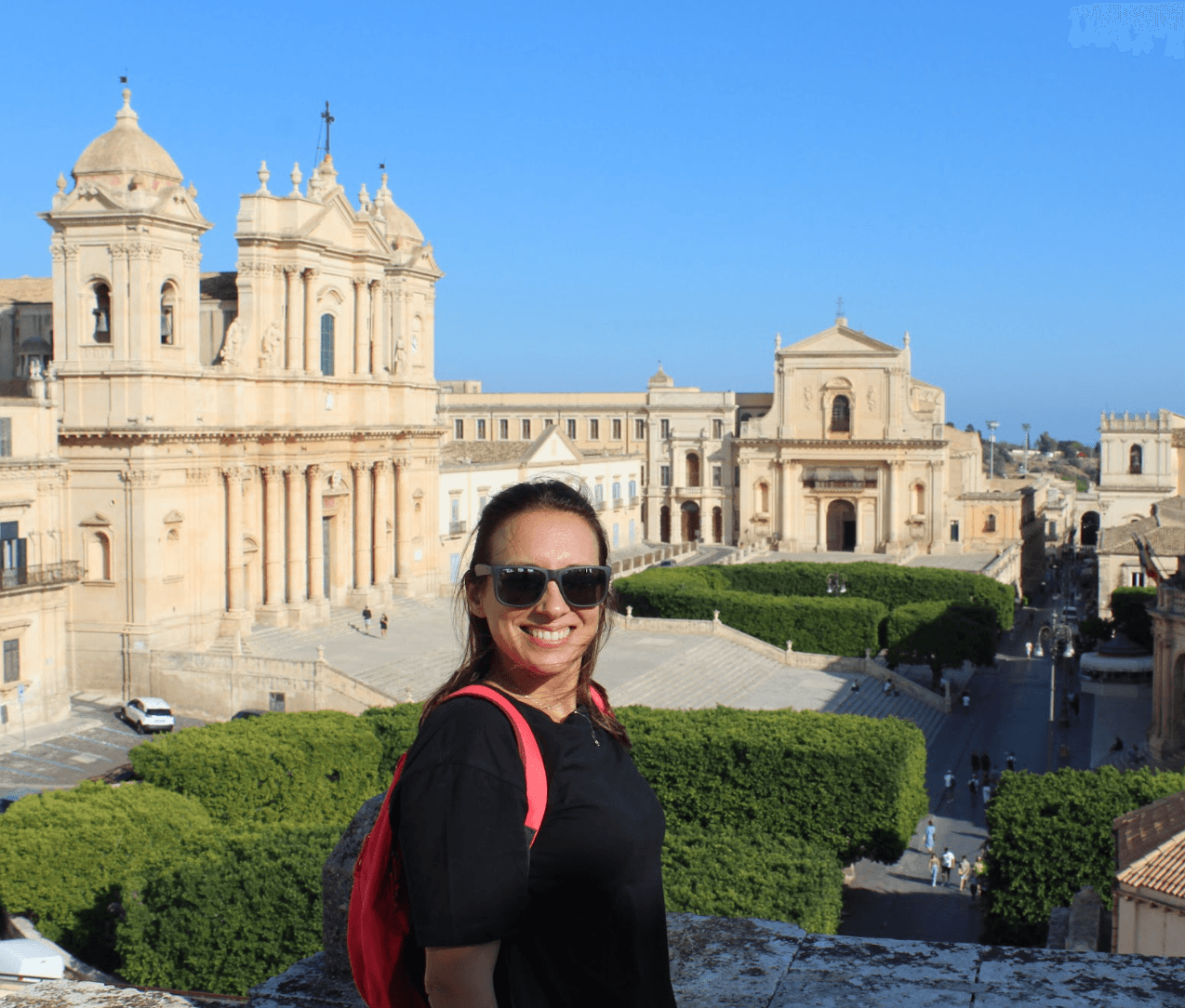 The image portrays a figure admiring a historic cityscape, marked by baroque architecture under a clear blue sky.