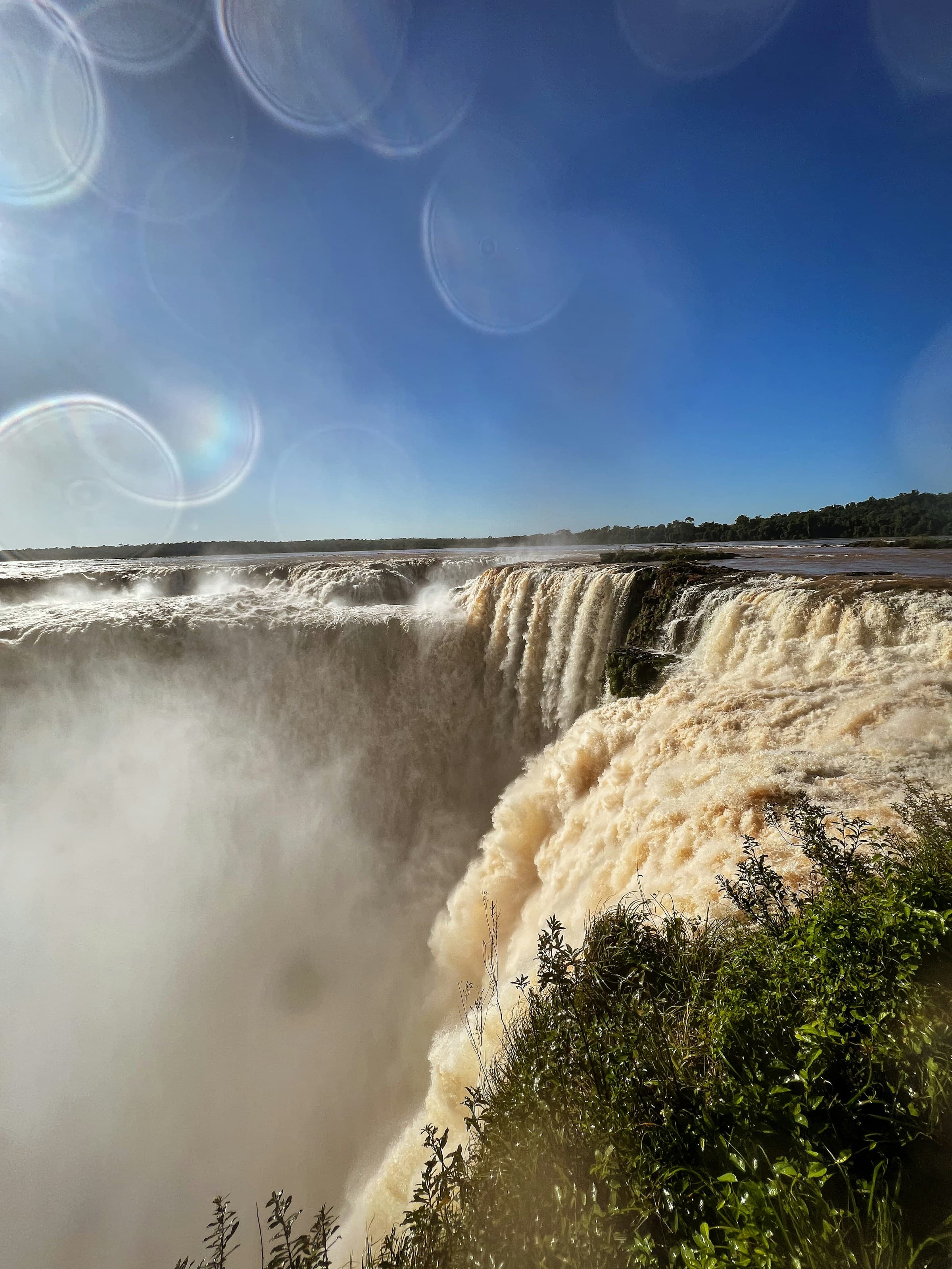 An image of waterfalls cascading downward with sun beams in the frame.