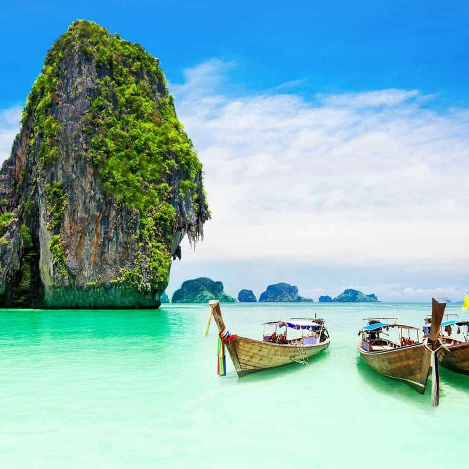 Boats in the sea next to a large hill during the daytime