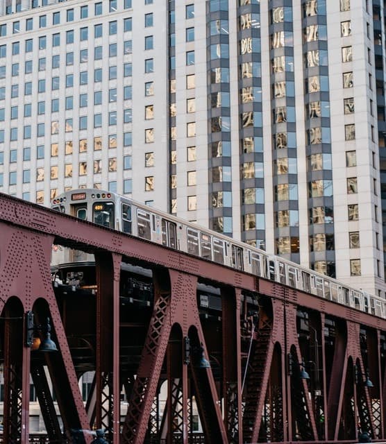 A view of the Chicago train and railroad with a tall skyscraper in the background.