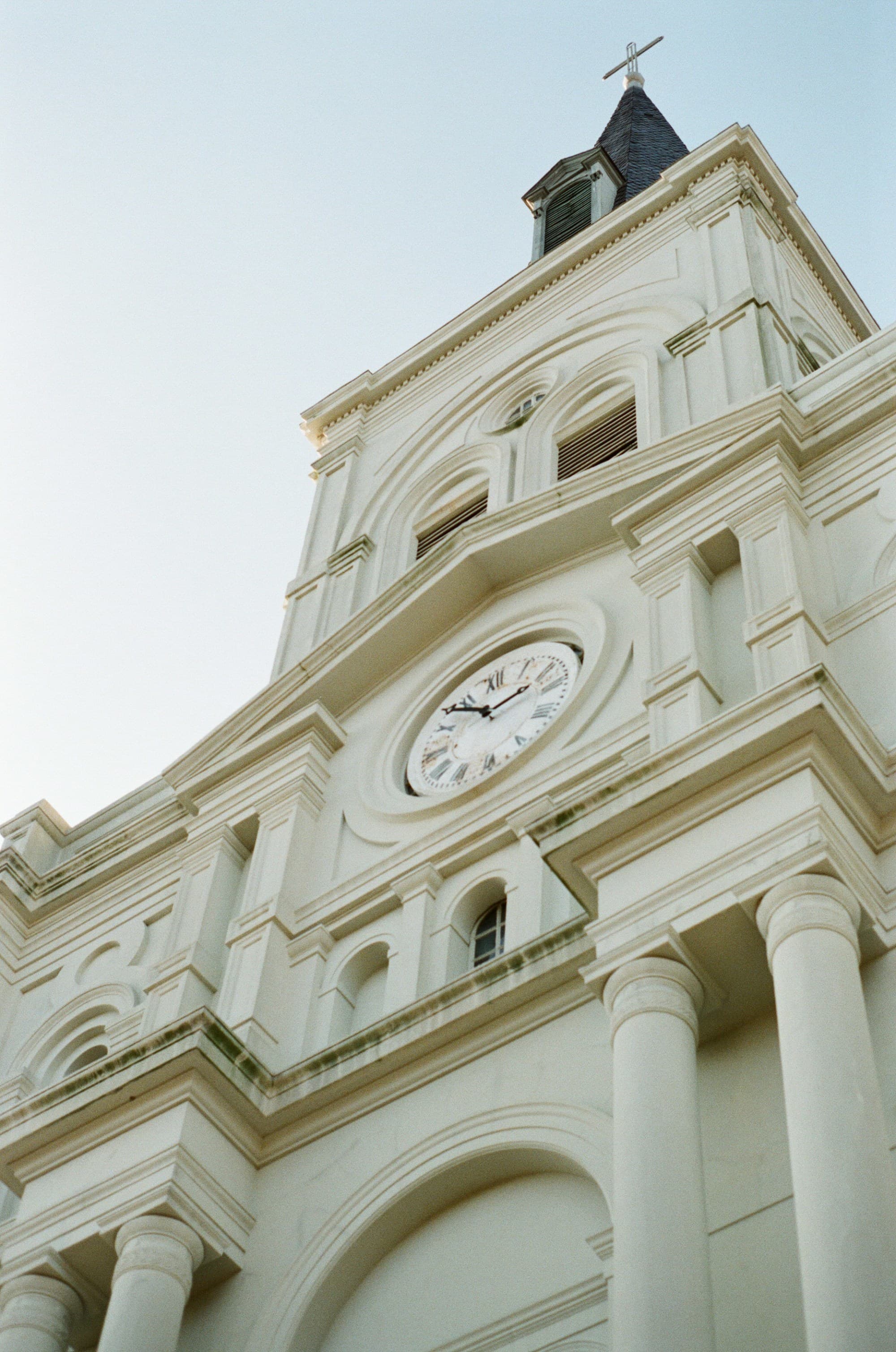 A low-angled shot of a white-colored building with a clock in the middle located close to the Mercantile Hotel, New Orleans