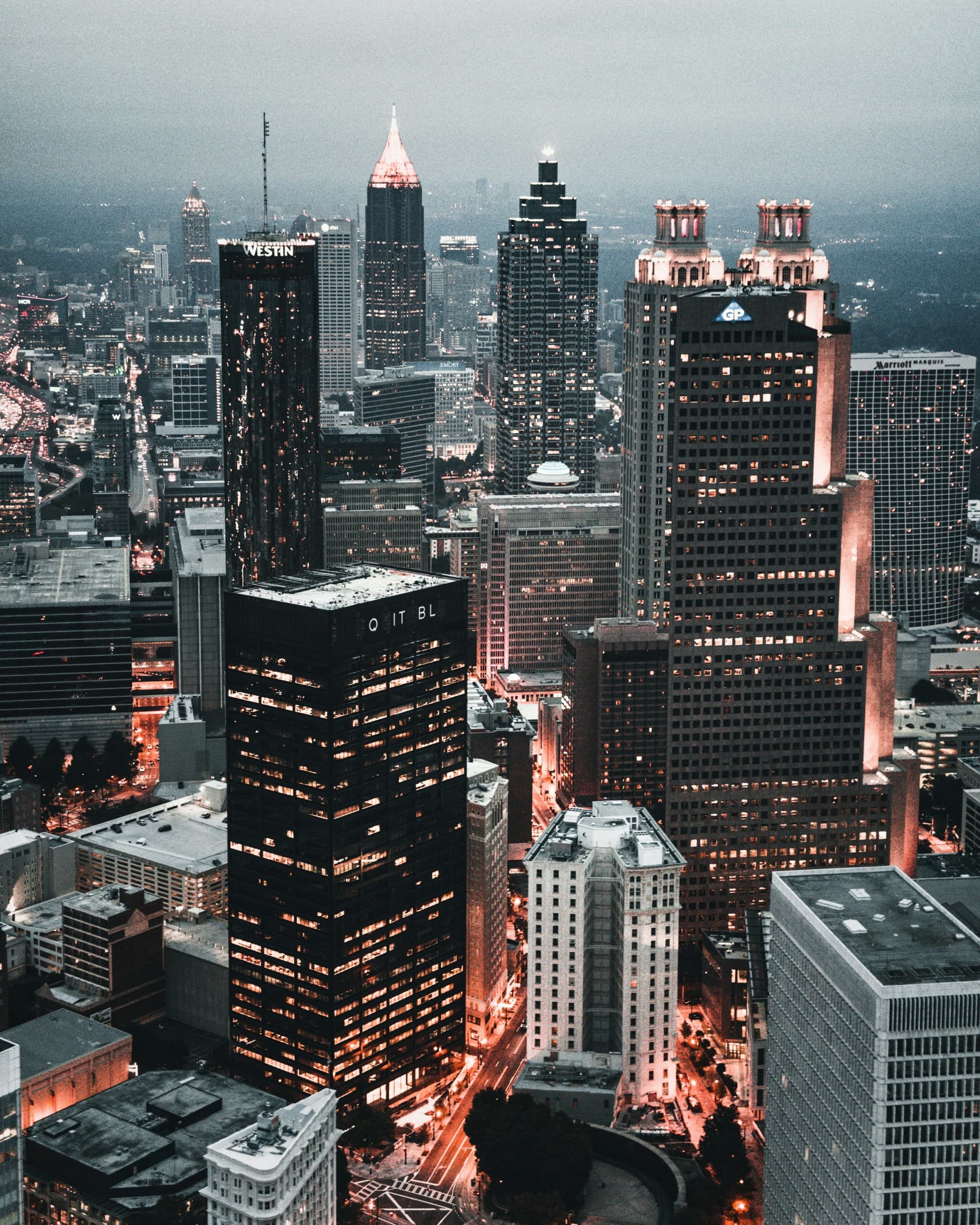 An aerial photograph of skyscrapers and a vibrant city lit up at night.