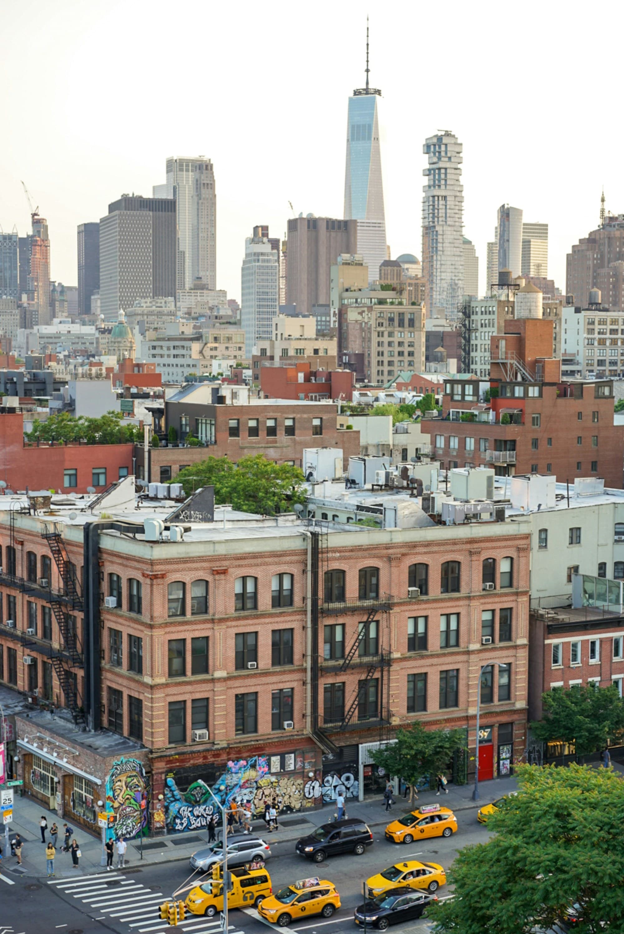 An aerial view of the New York city skyscrapers and smaller brick buildings and yellow taxis in the street