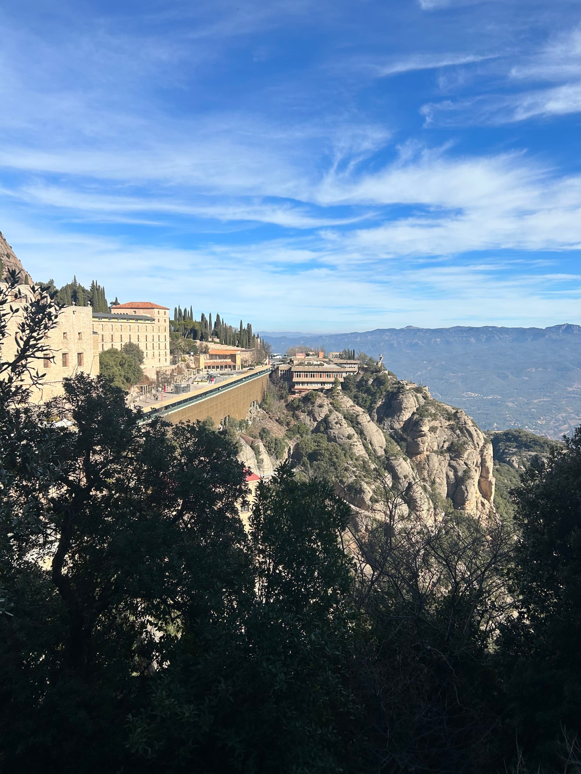 View of a building on a cliff from behind the trees.