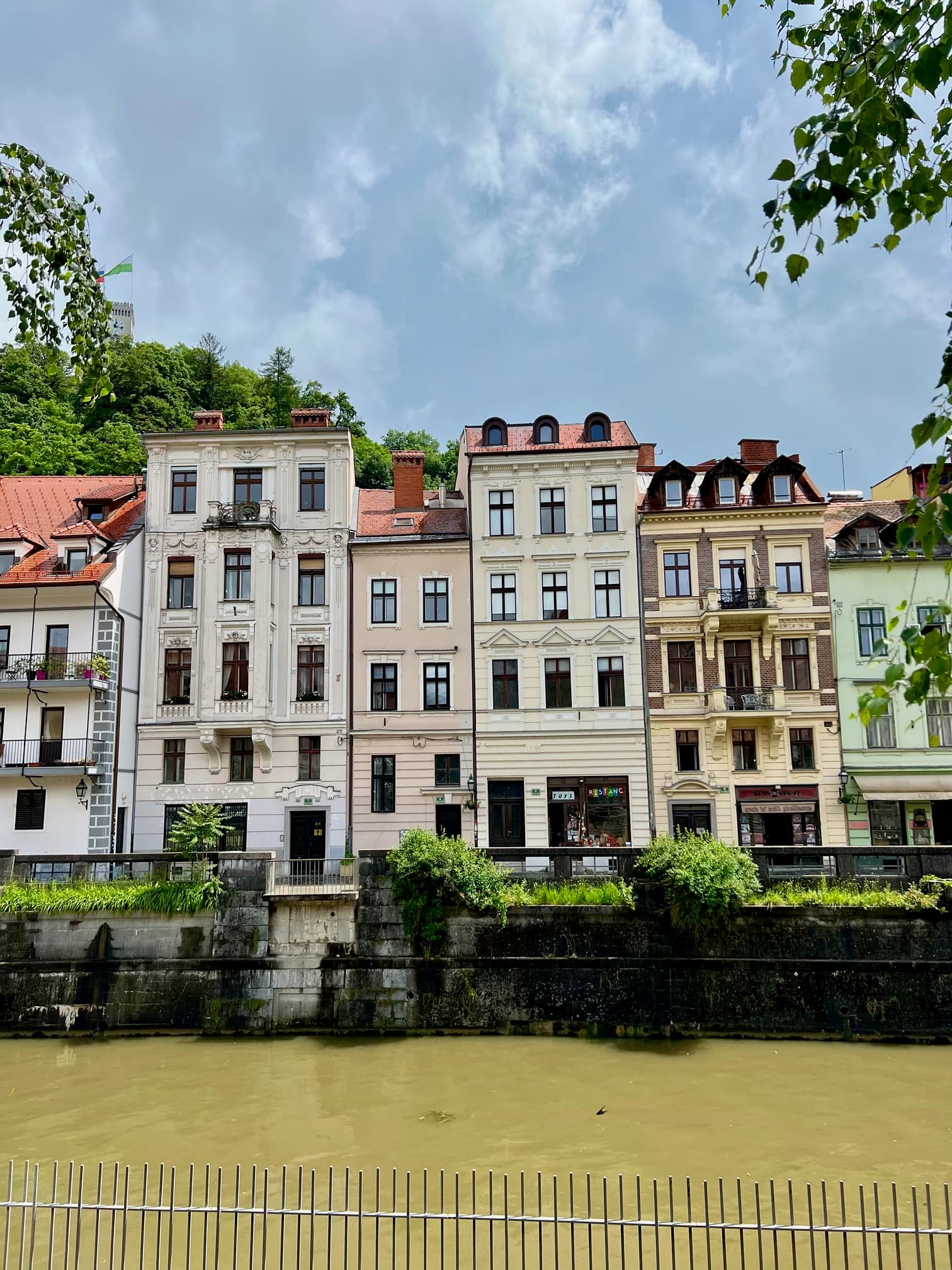 A city canal in front of buildings and a walkway.
