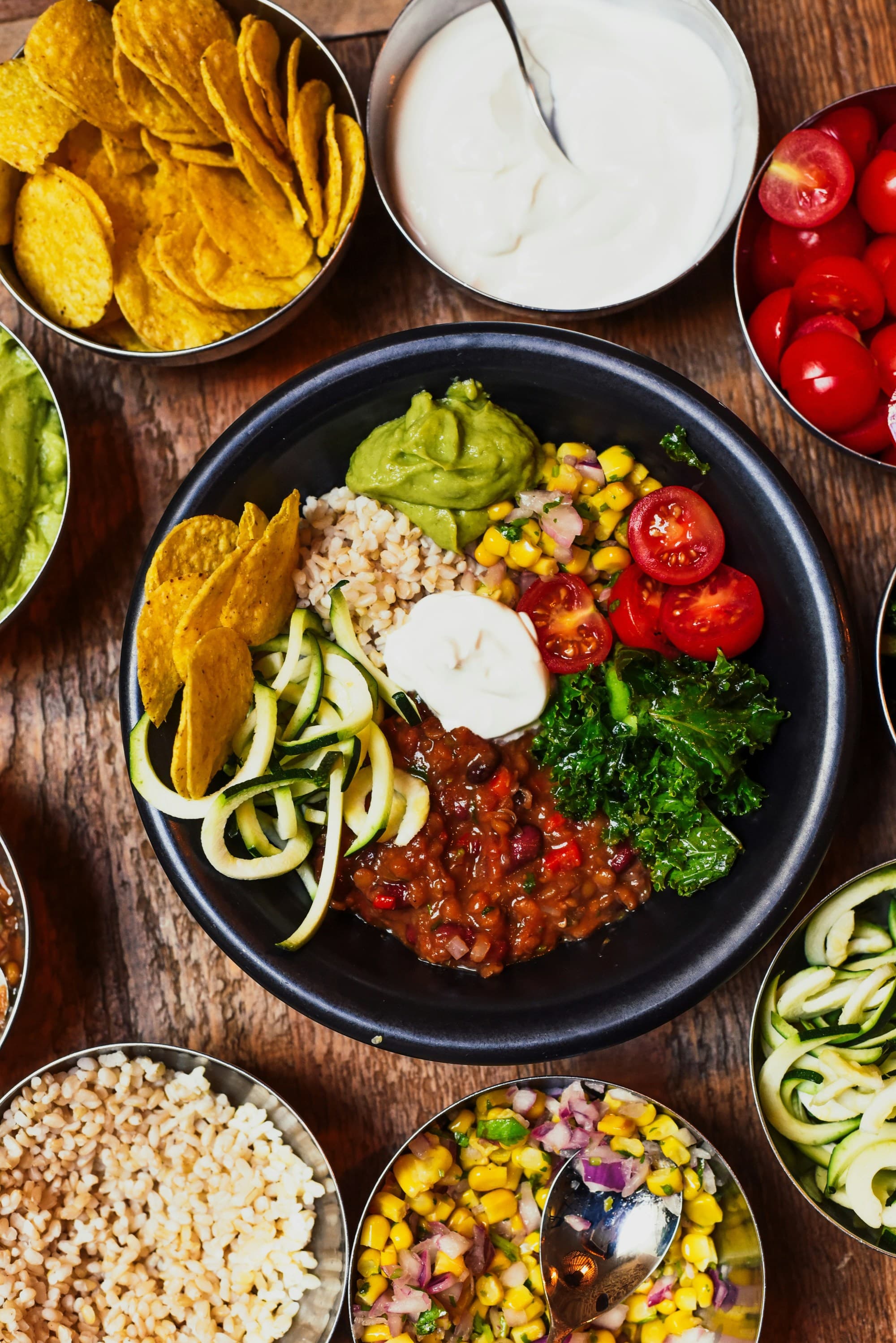 Multiple bowls of vegetables laid out on a wooden table