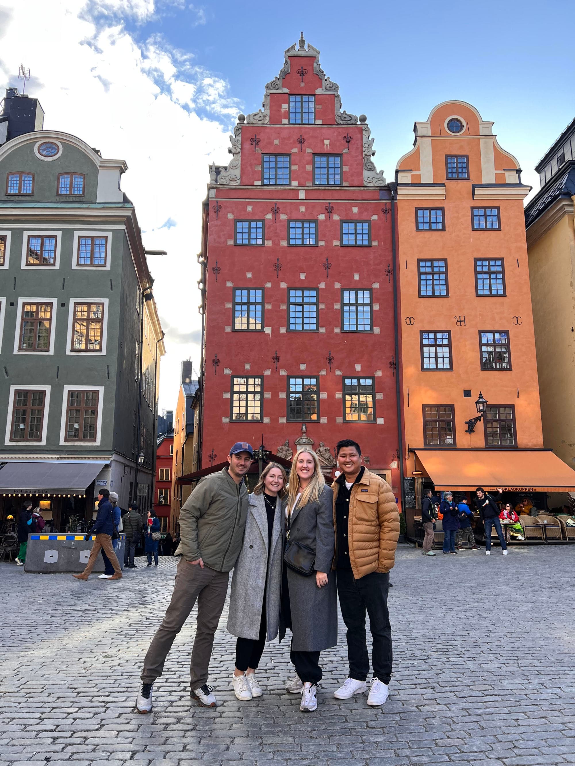 A group of people standing in front of colorful buildings on a street.