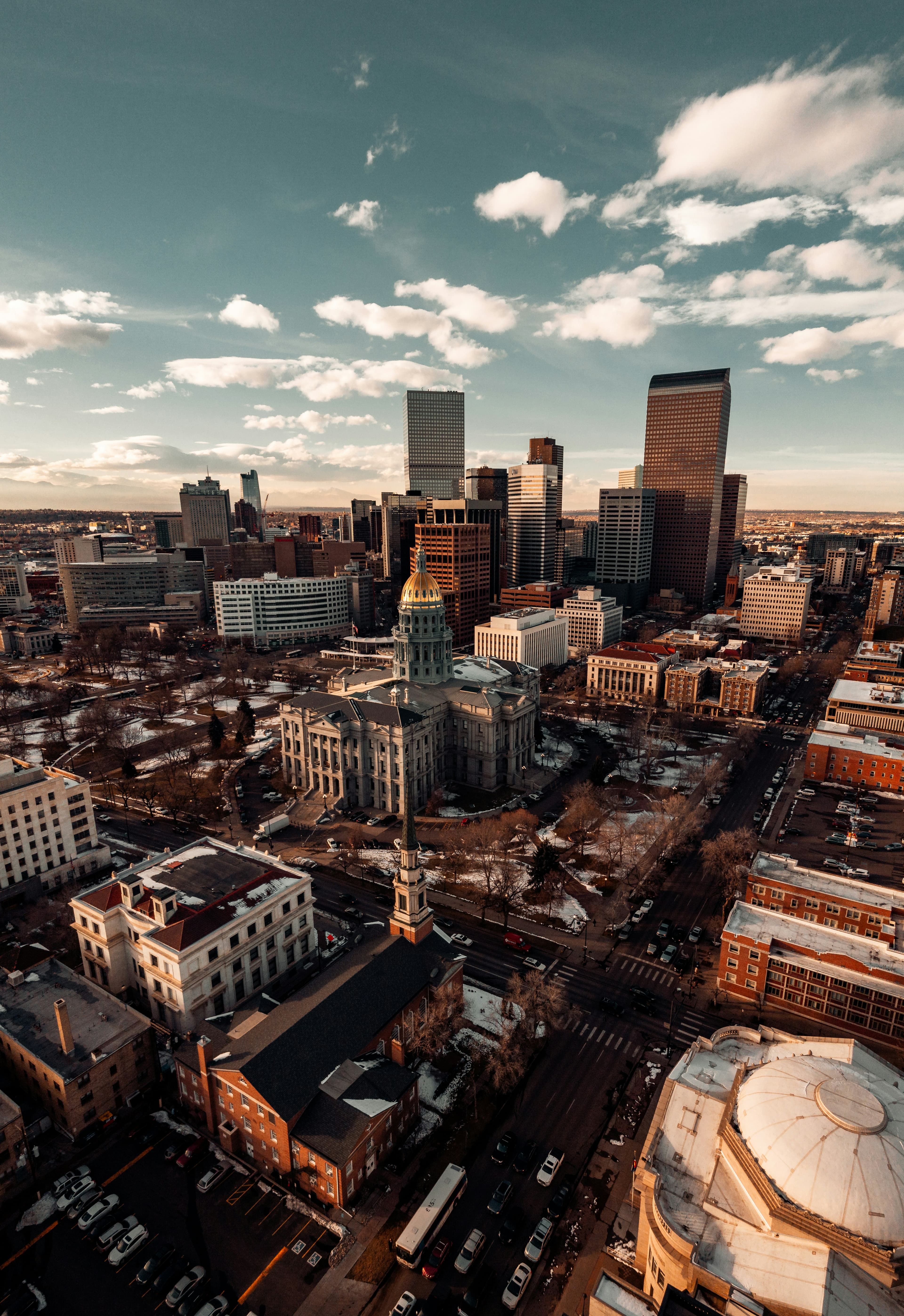 The Denver skyline with tall buildings on a sunny day with clouds.