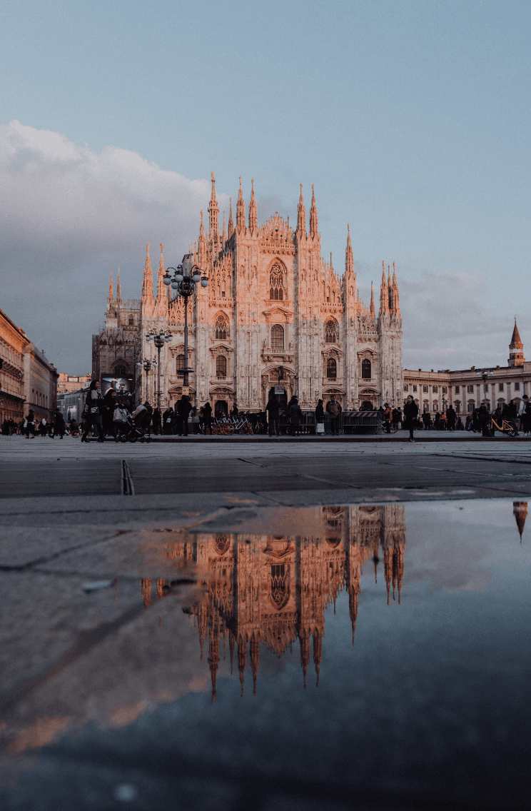 A view of the duomo in Milan with an orange and blue sky in the background.