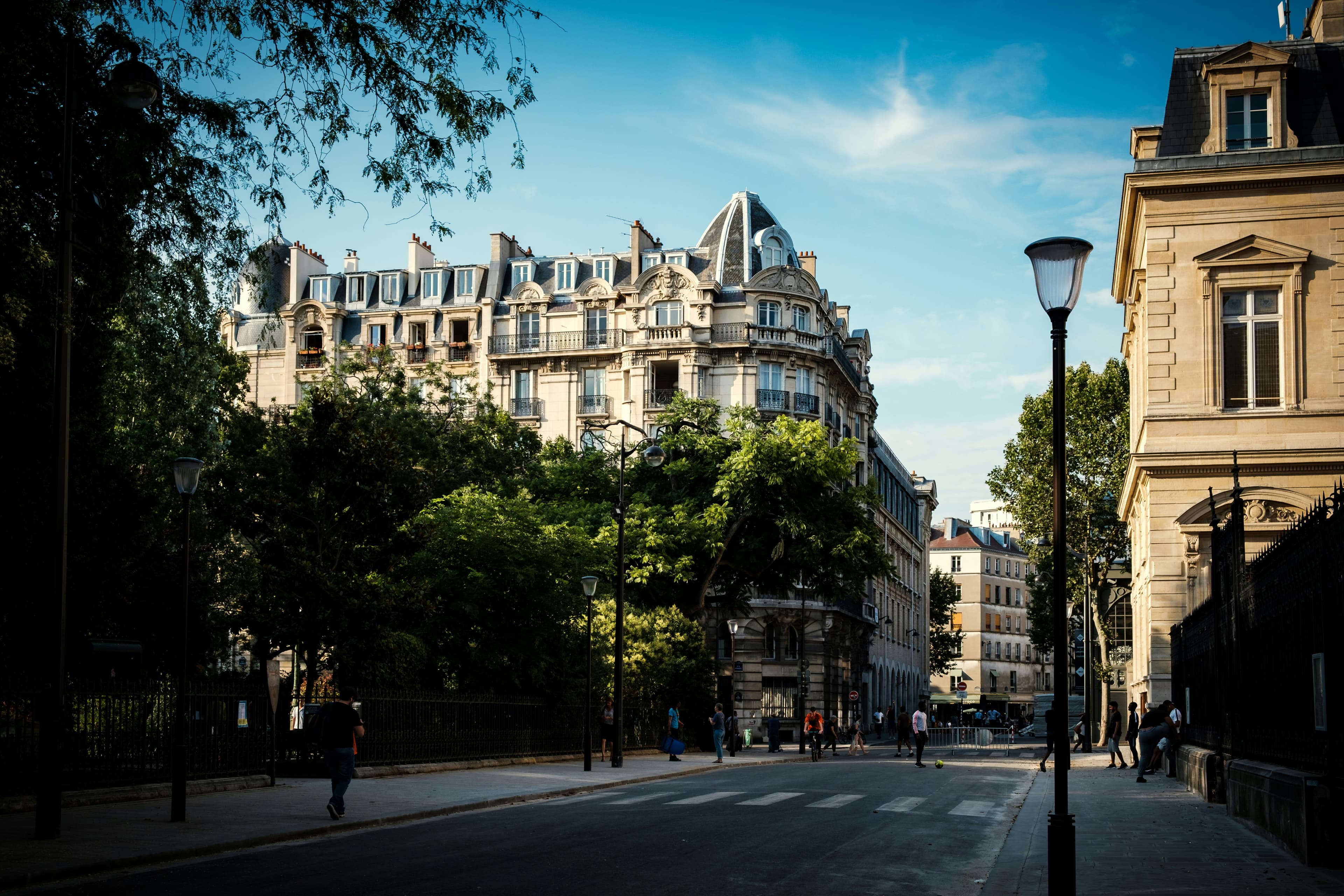 A street in the Paris 3rd arrondissement, with a large Hausmannian building next to a green park.