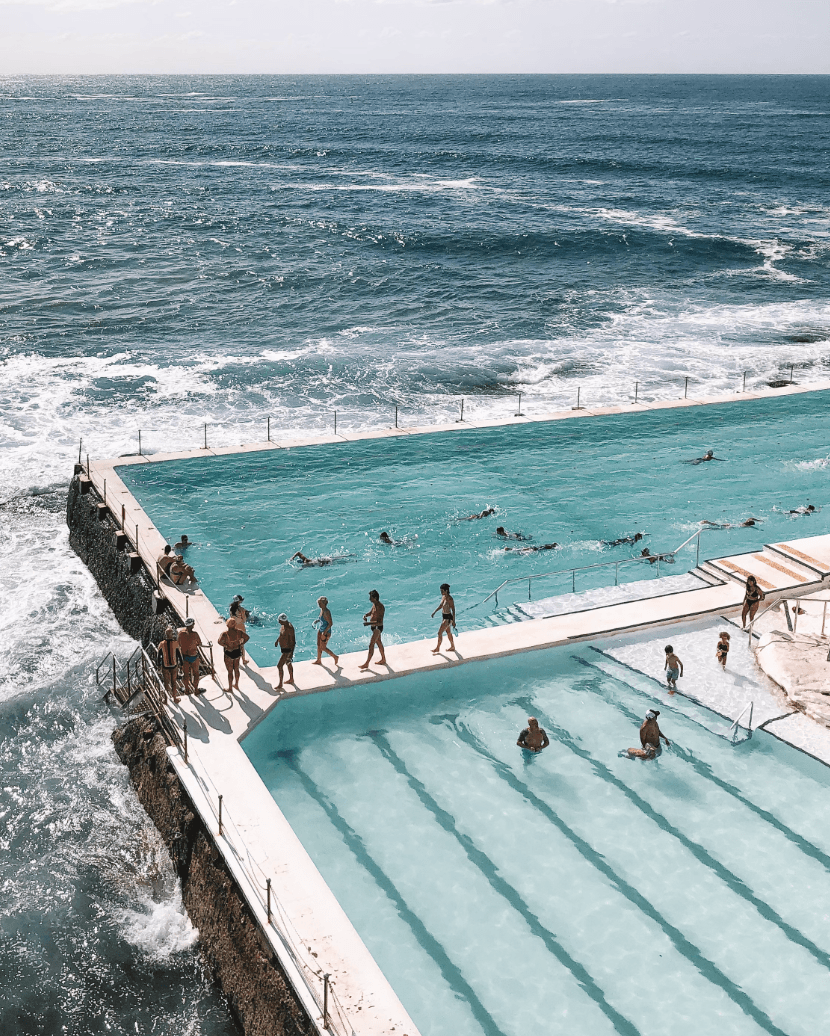 A view of people standing near a swimming pool and ocean.