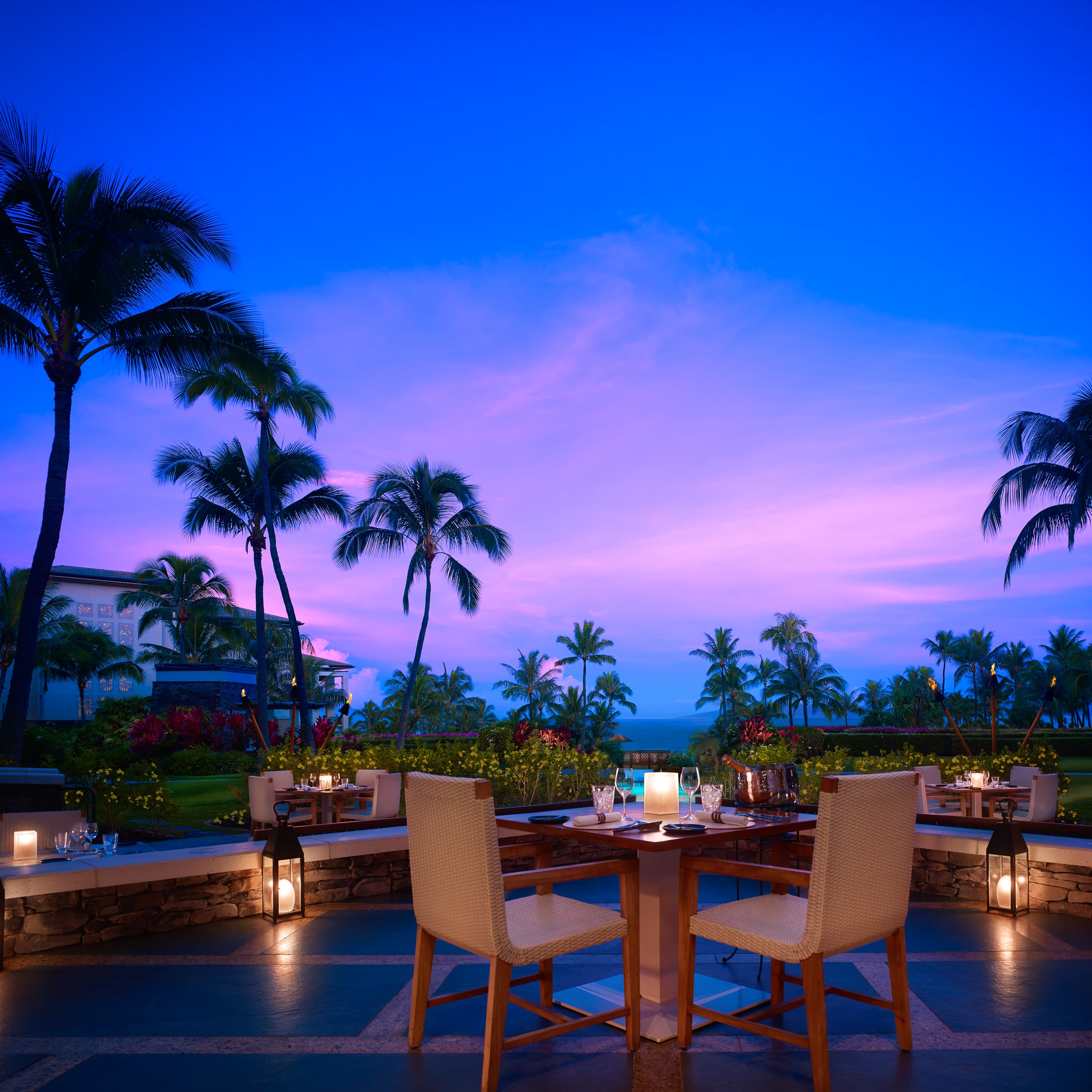 two chairs and a table with palm trees in the background