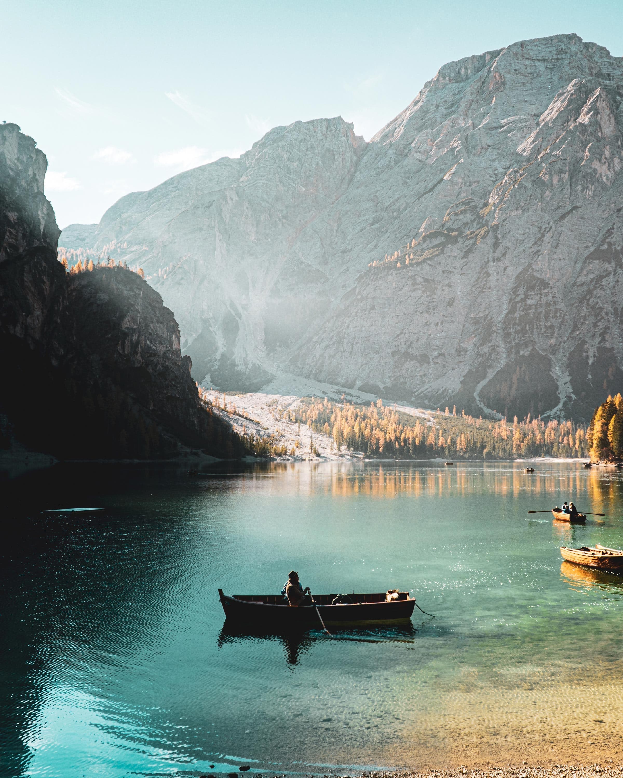 Person sits in rowboat in blue waters with mountains covered in snow in the background in Italy