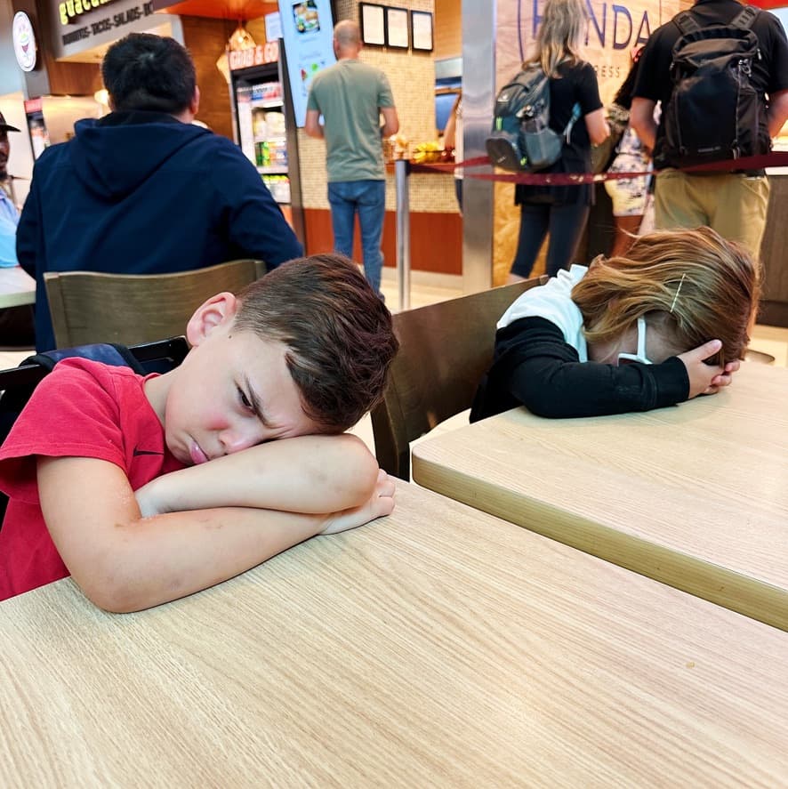Two kids in tears with their heads down on a table.