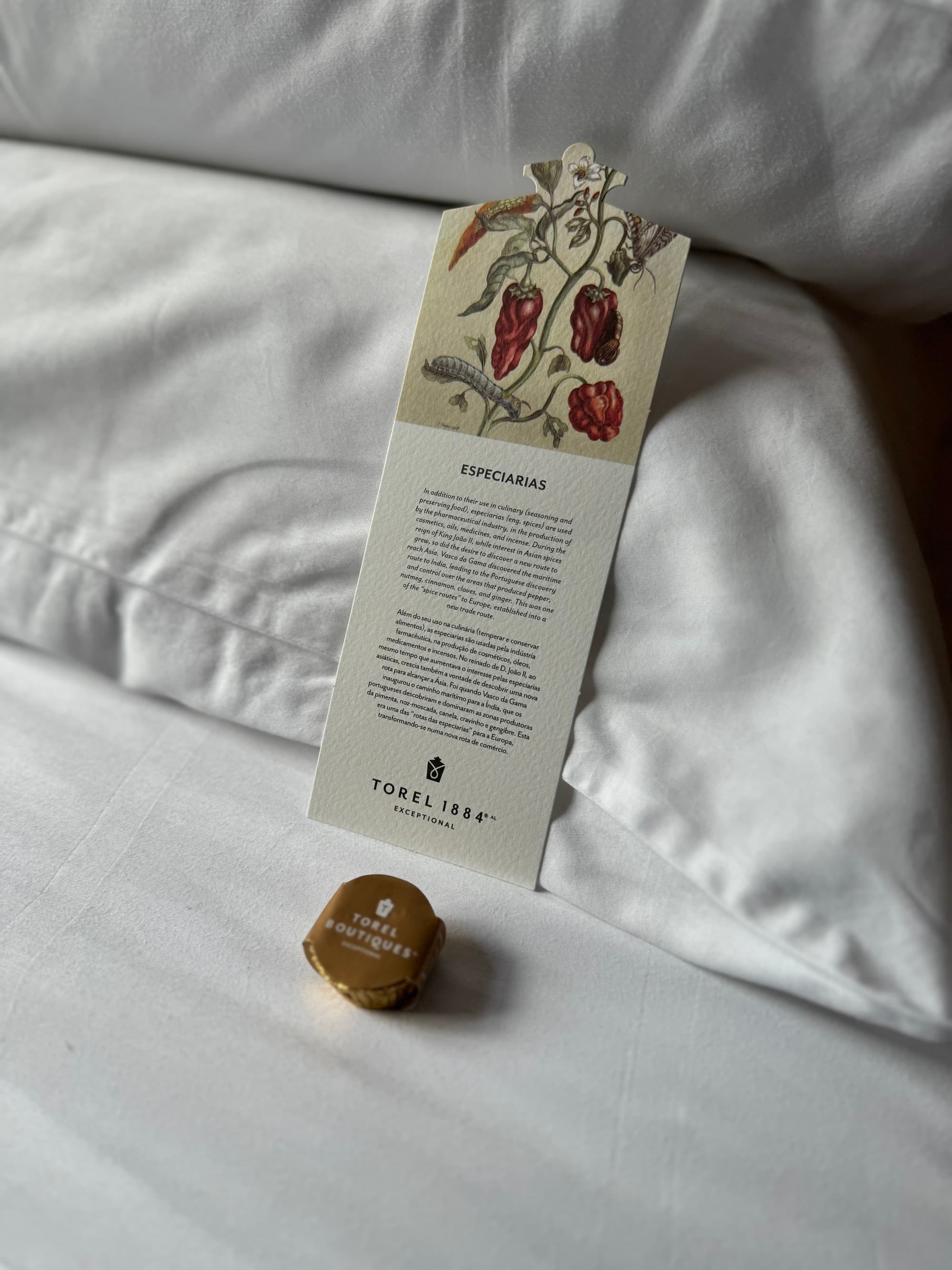 A note and wrapped chocolate on a bed