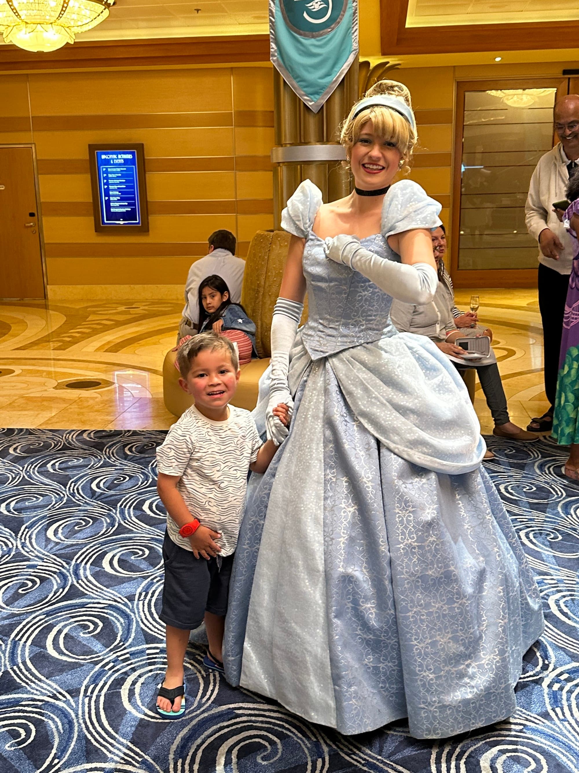 A character dressed as Cinderella holds hands with a toddler.