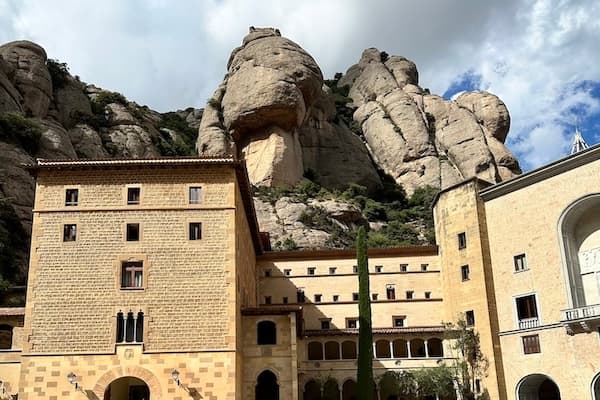 A brown-brick building at the bottom of a rock formation
