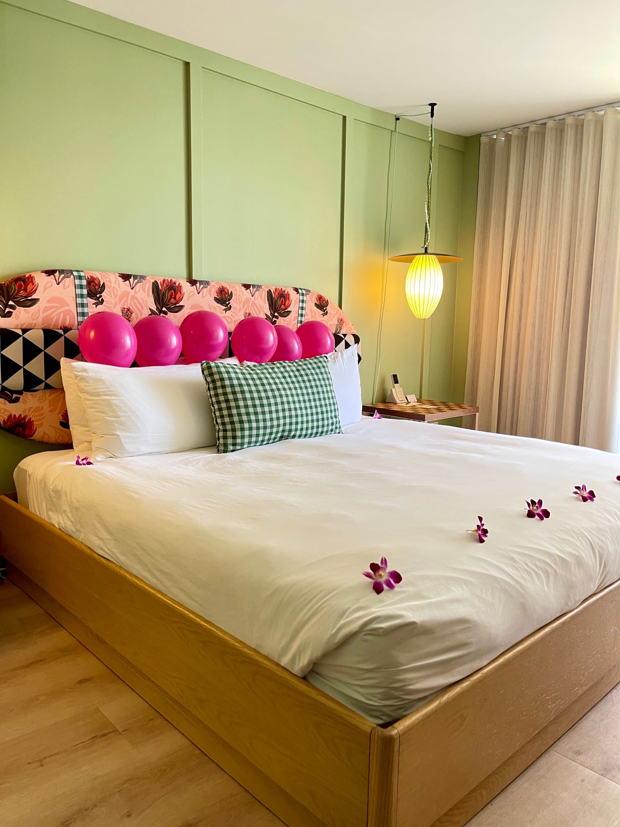 A hotel room suite with a patterned bed frame behind a white bed