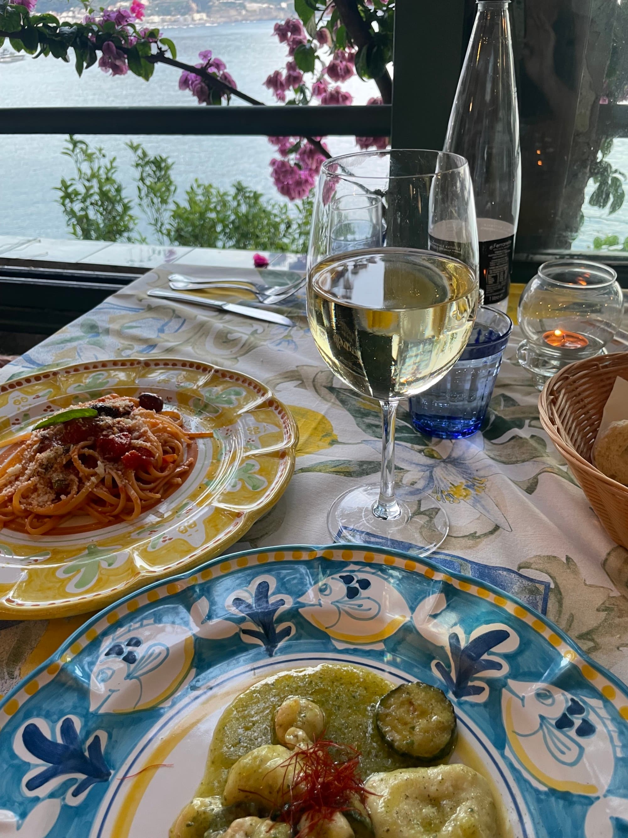 Plates of food and glasses on wine sitting on an outdoor table