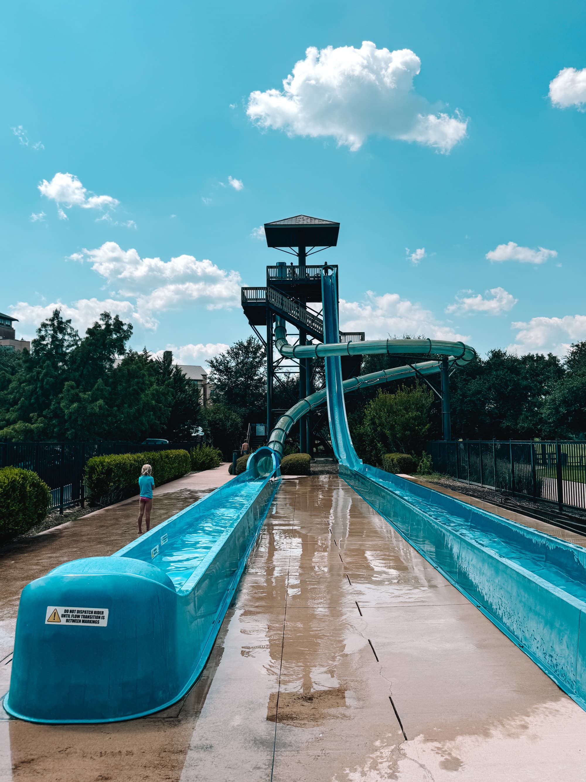 Water park slides reach to the sky on a sunny day dotted with clouds.