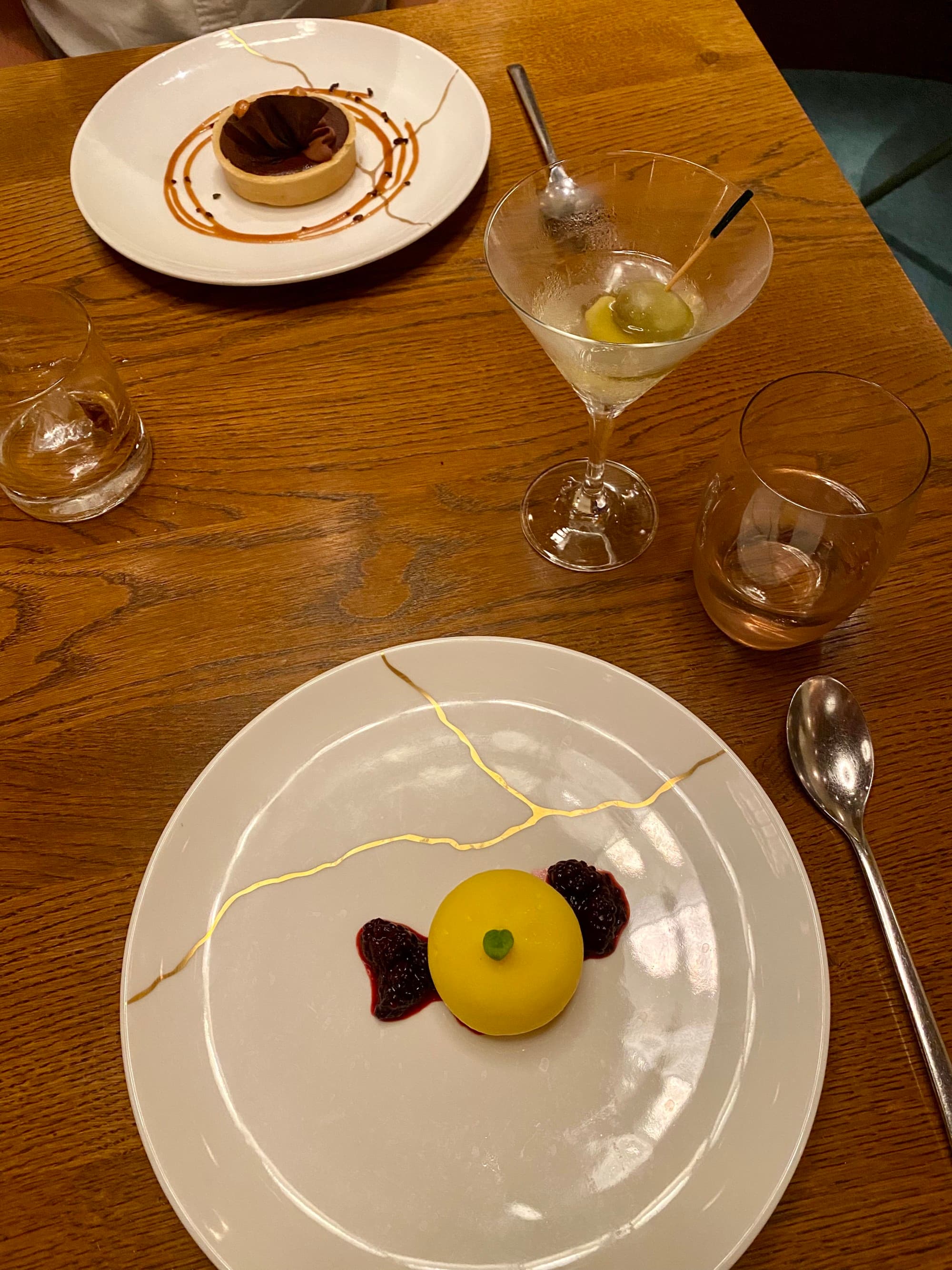 Two plates with small desserts next to a cocktail glass