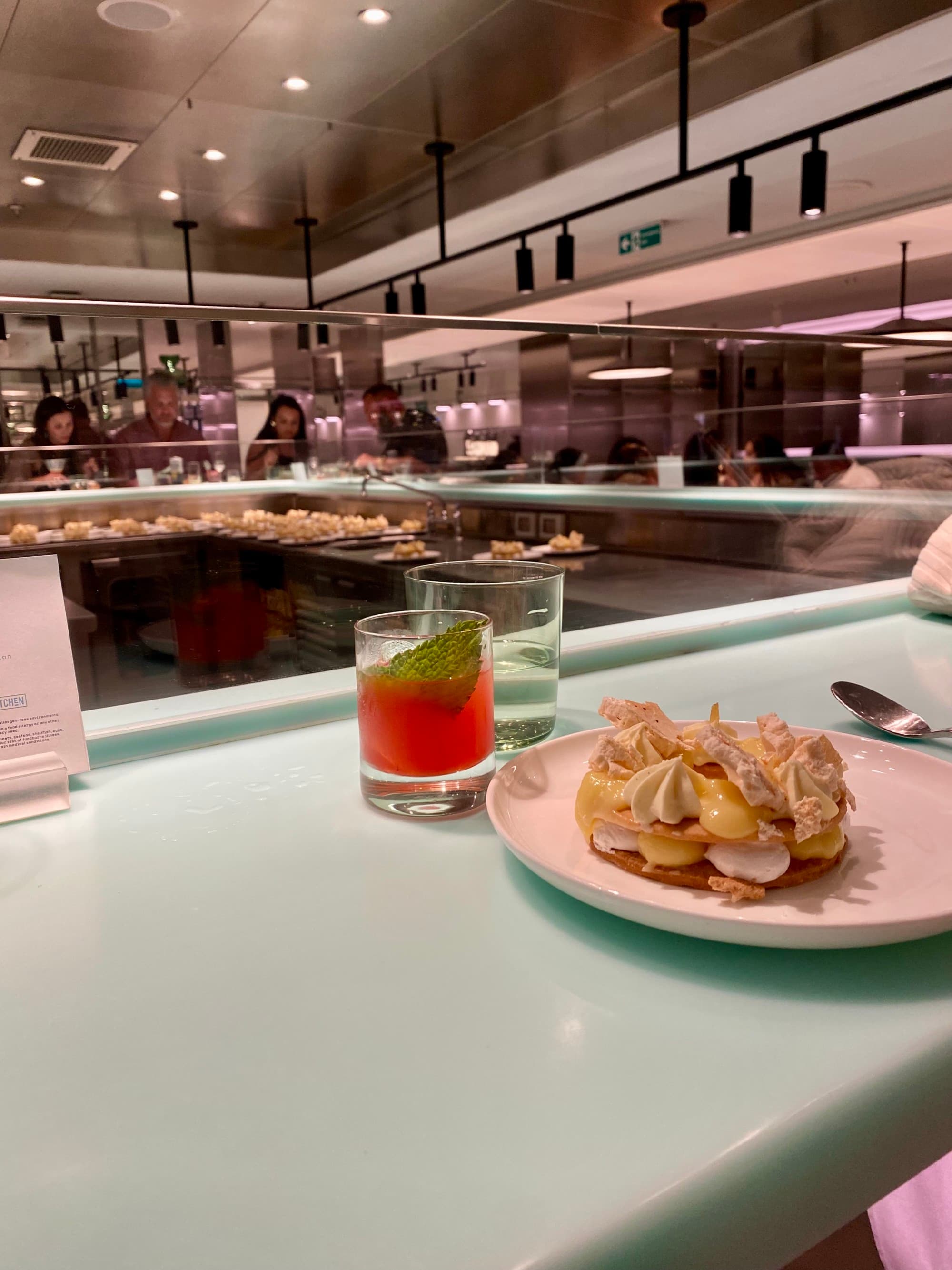 Food on a plate and cocktail glasses sitting on a bar