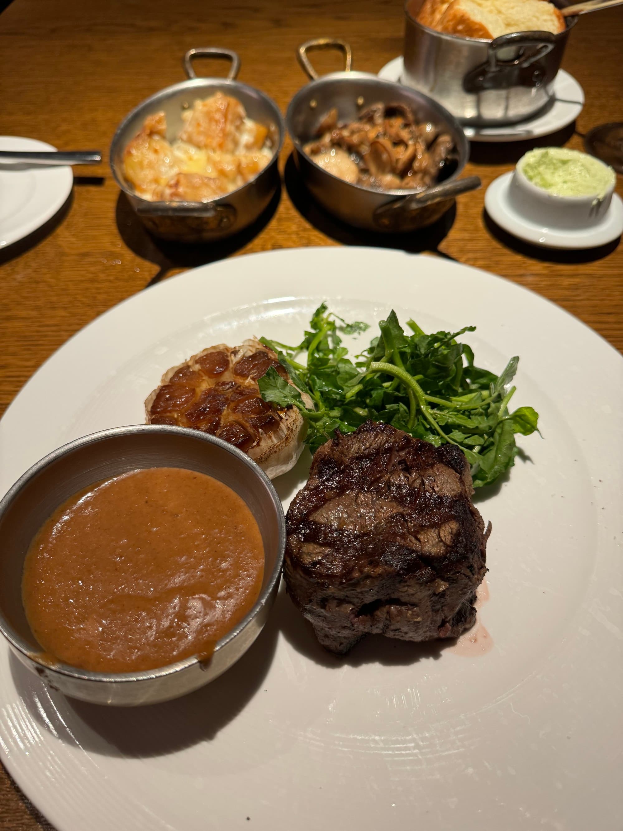 Steak and broccolini on a white plate on a table.