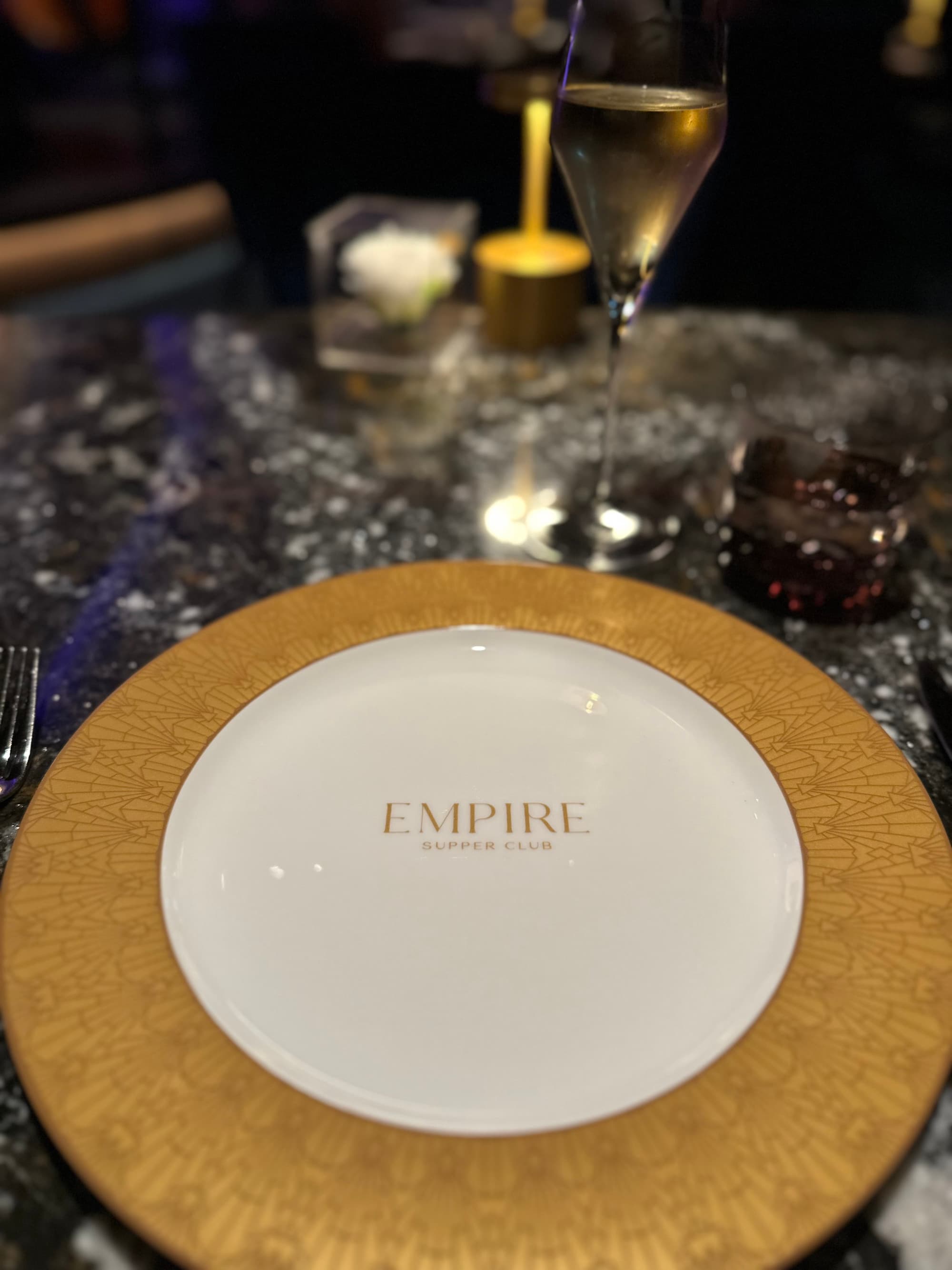 A place setting in Empire Supper Club on a marble table surrounded by glassware.