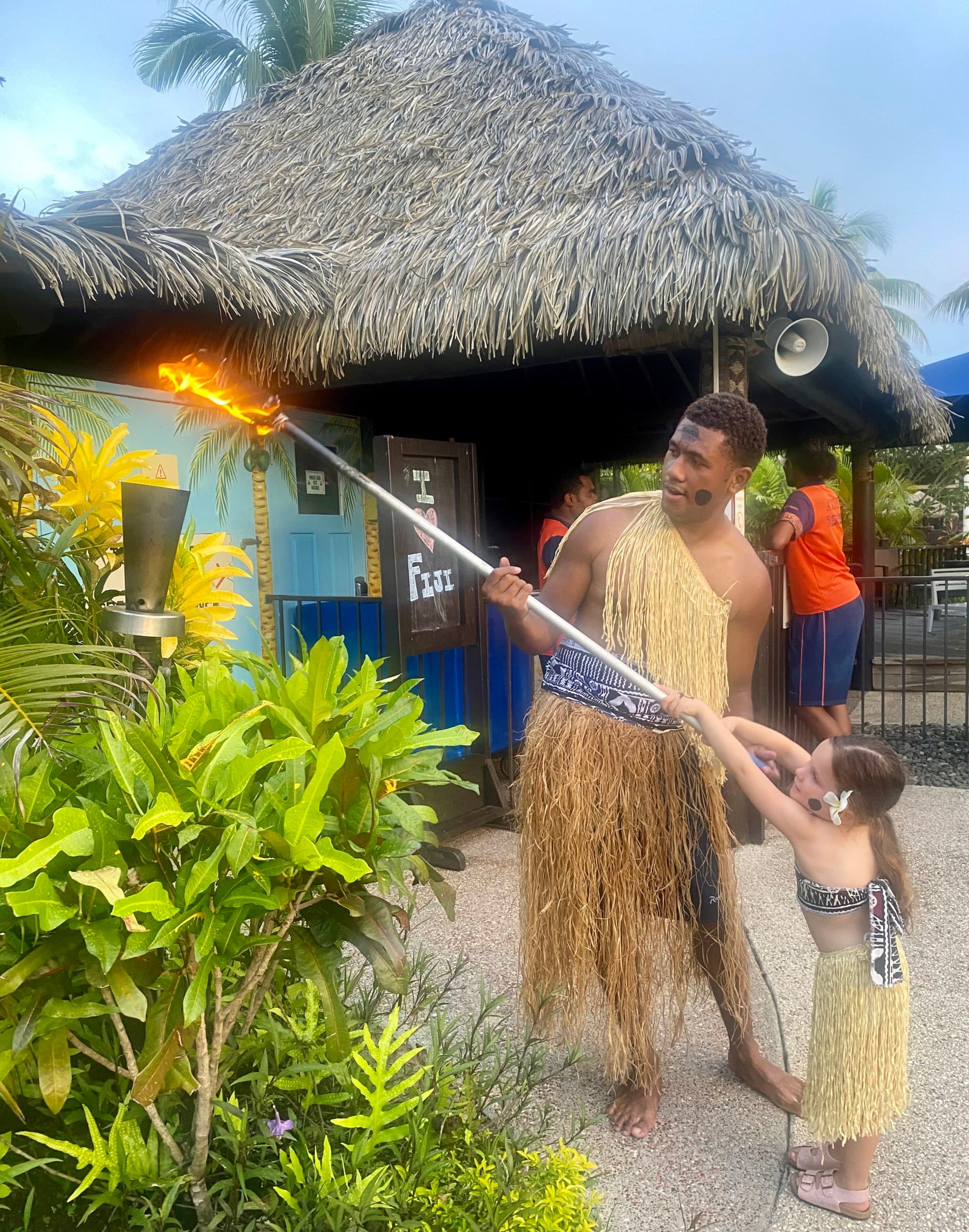 Kids lighting torches with the hep of an employee.