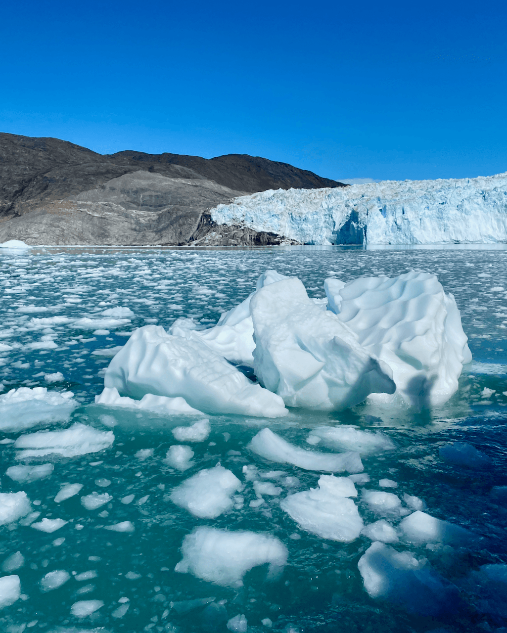 A view of the ocean with parts of iceberg and Eqi Glacier in the back in Ilulissat, Greenland