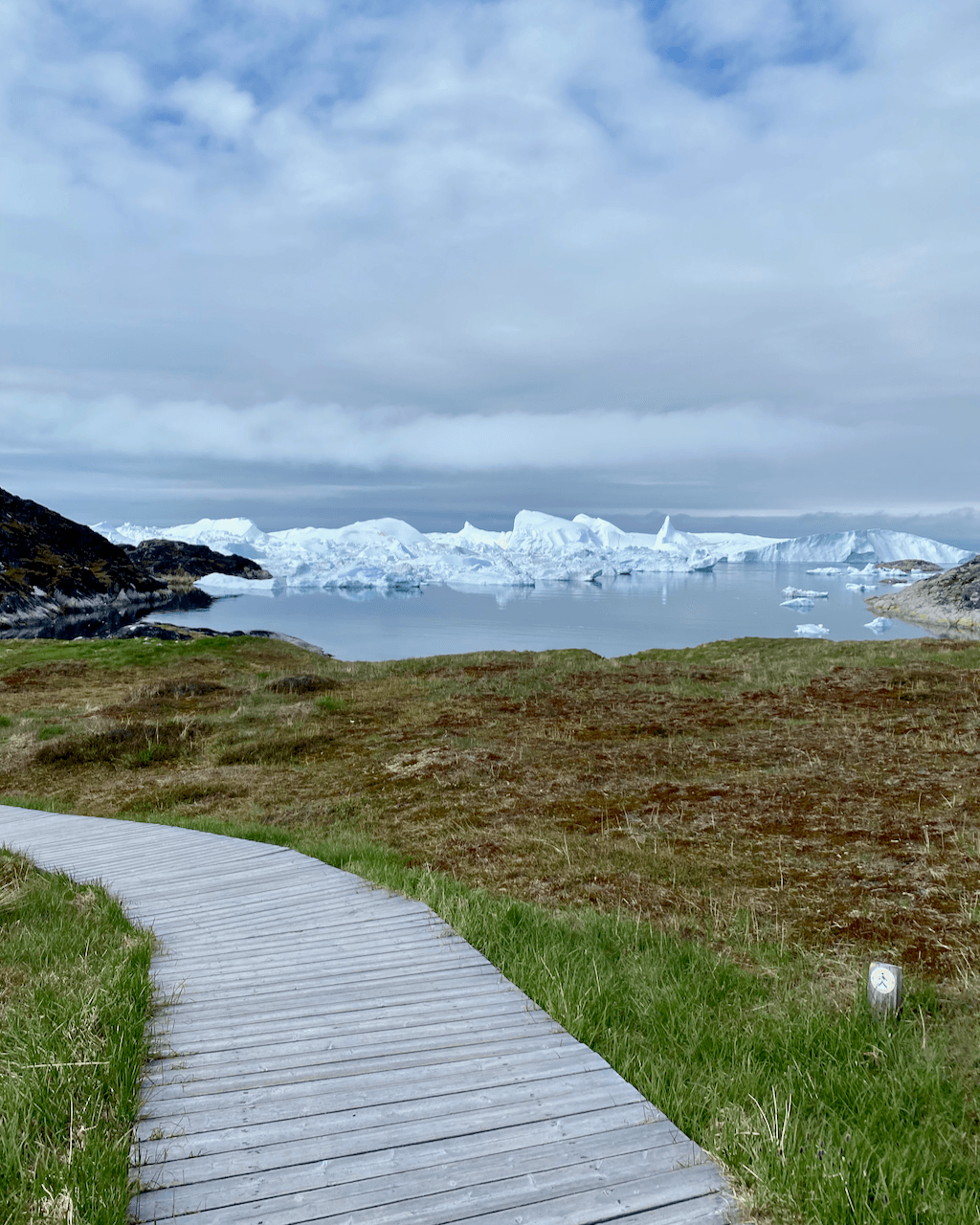 A path down towards the ocean with icebergs in Ilulissat, Greenland