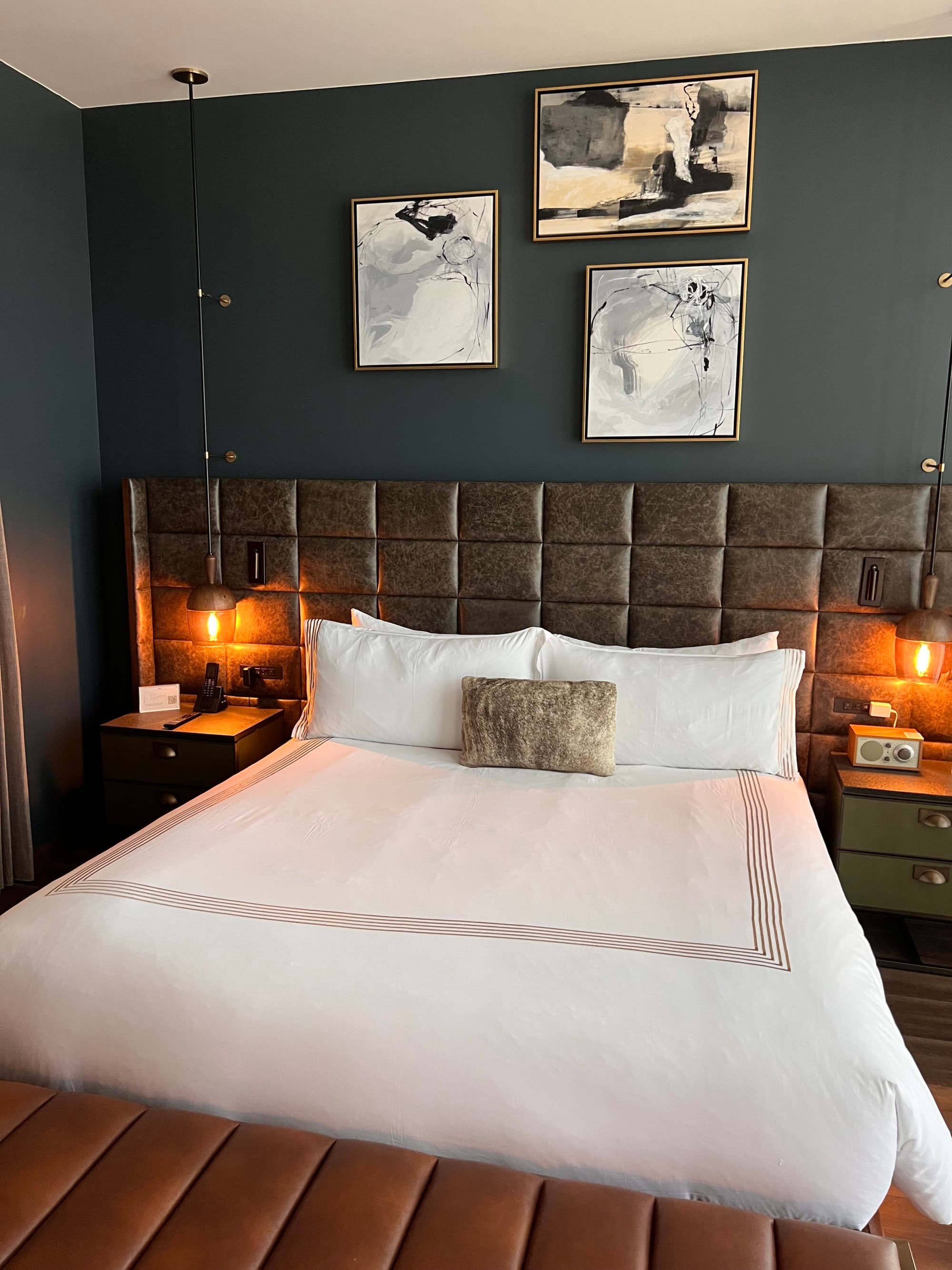 A white bed in the center of a hotel room