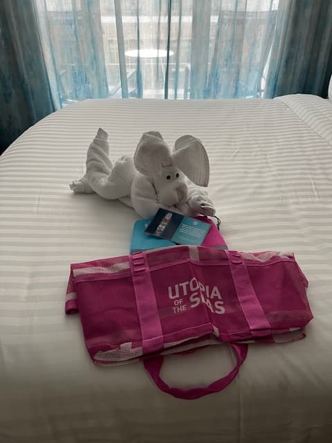 A bed with gifts and a towel folded into the shape of a mouse.