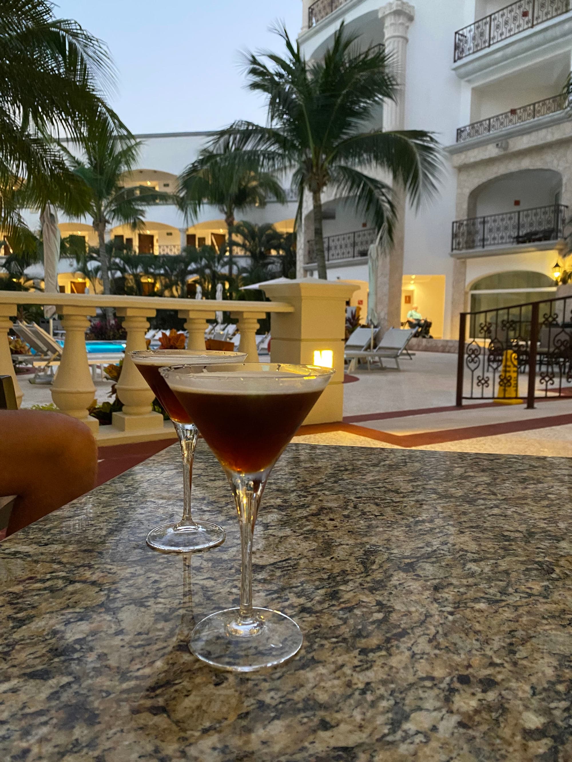 Two drinks in martini glasses sitting on an outdoor table