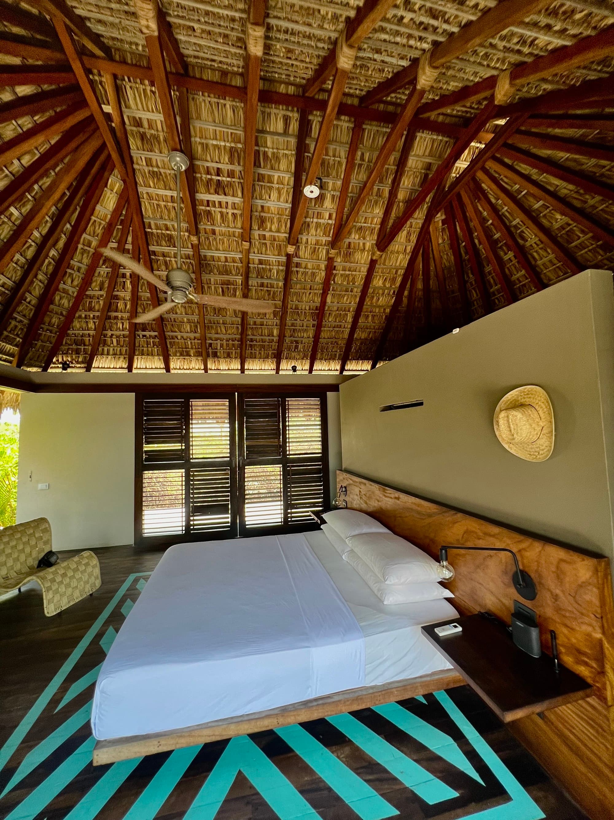 Bungalow interior with a queen-sized bed with white sheet.