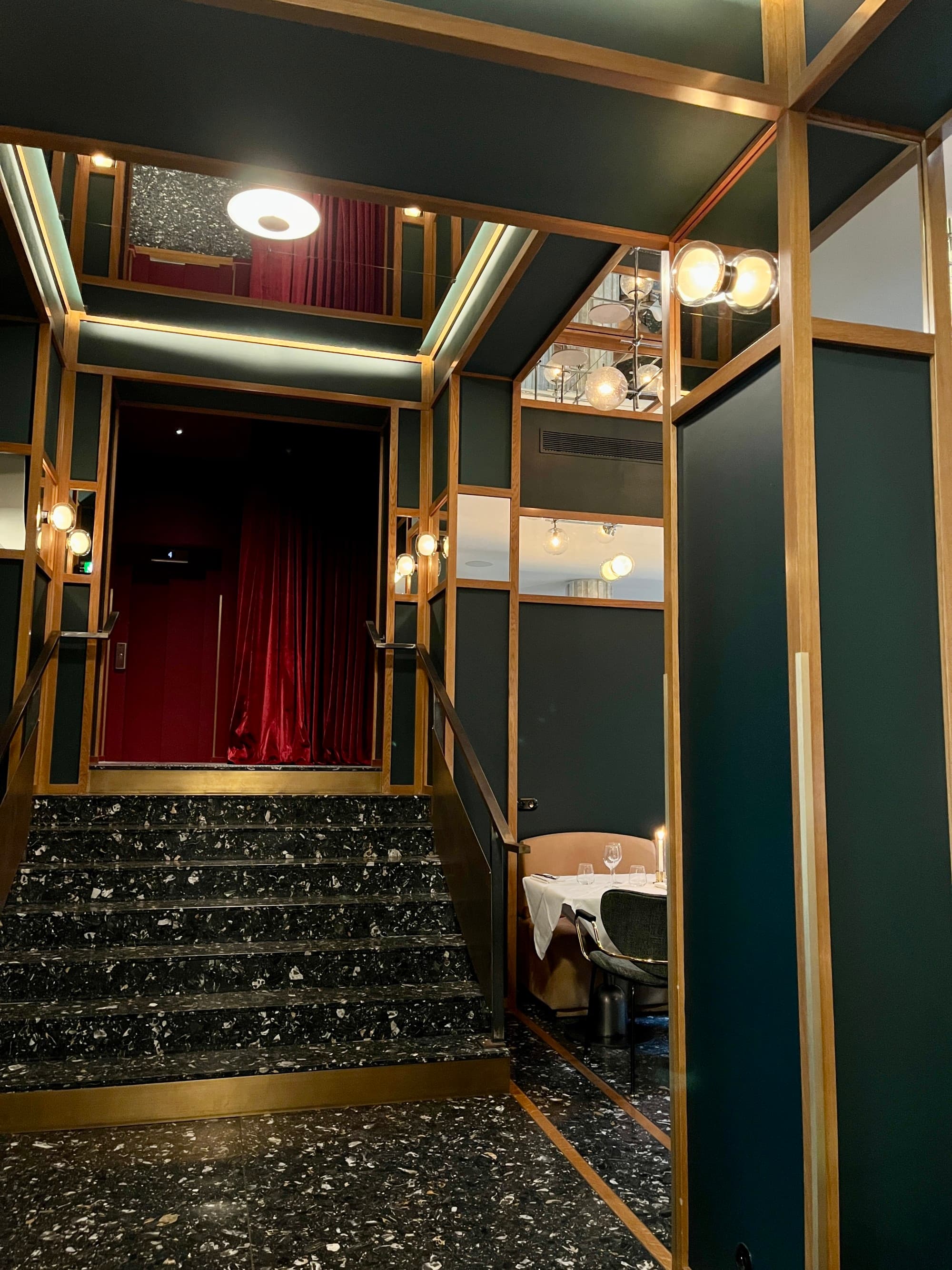 Hotel lobby with dark green walls and black marble floors.