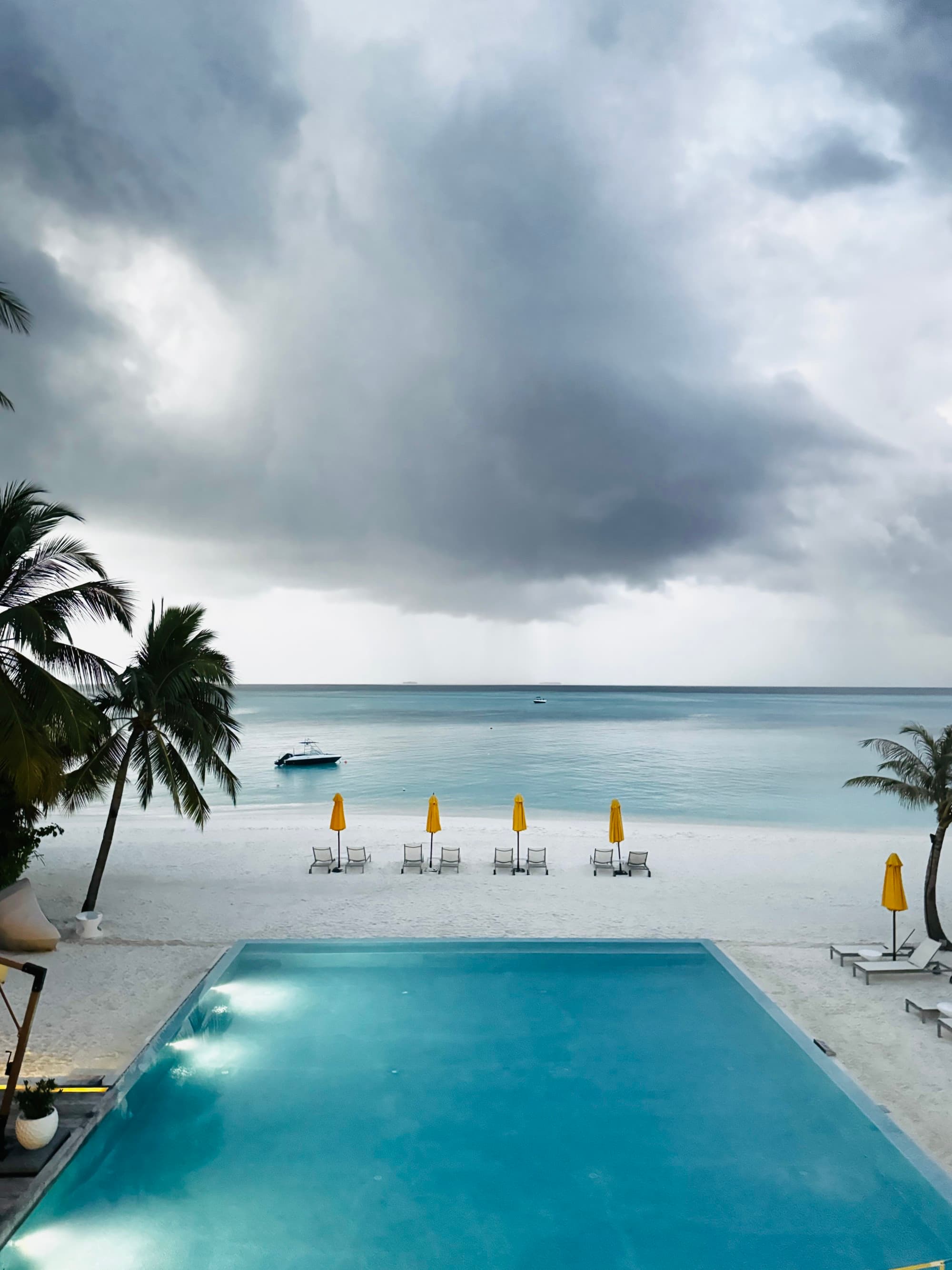 Pool on the beach with lounge chairs in the background.