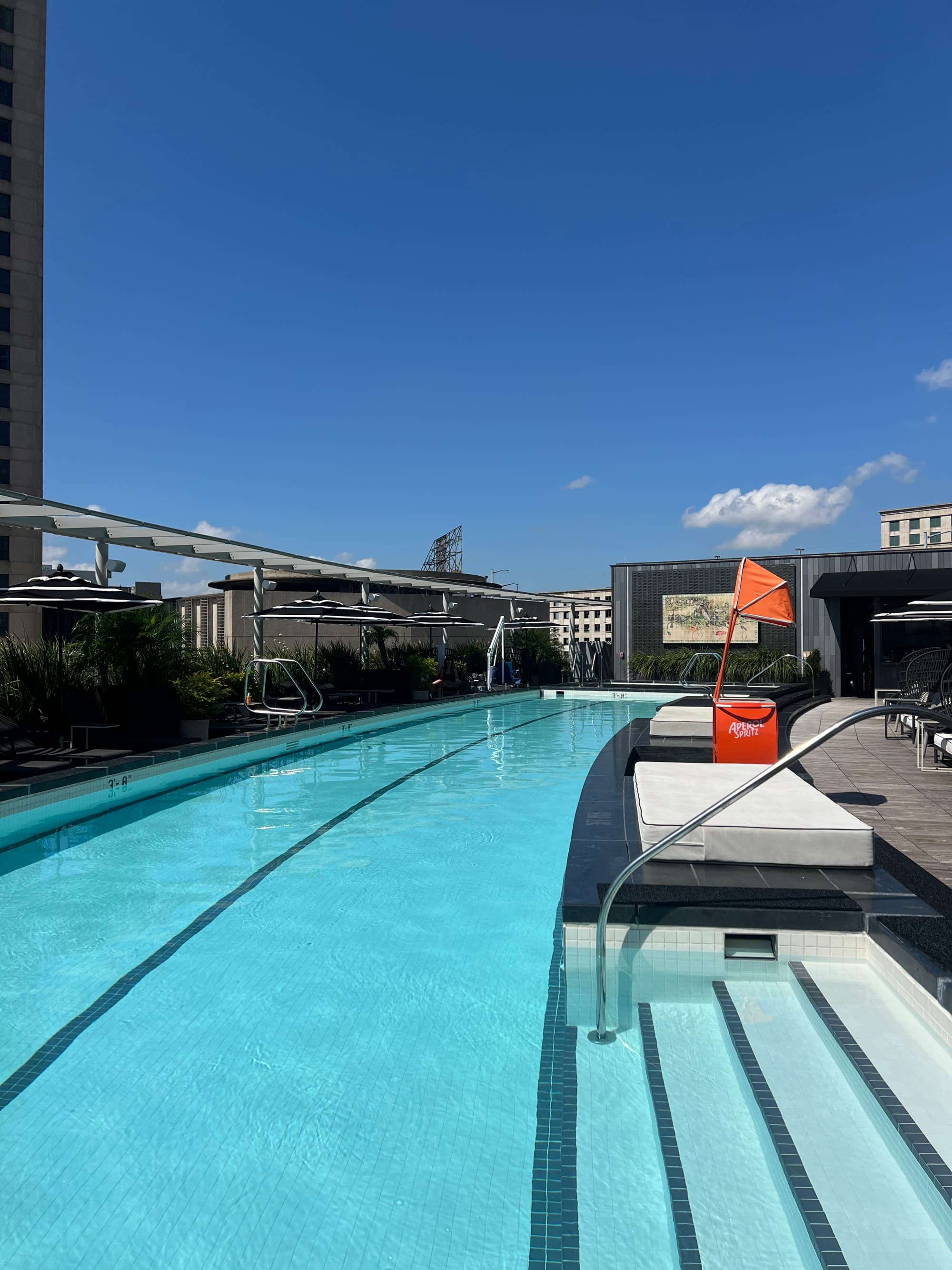 A view of a two lane lap pool, stairs going into the pool and a blue sky.
