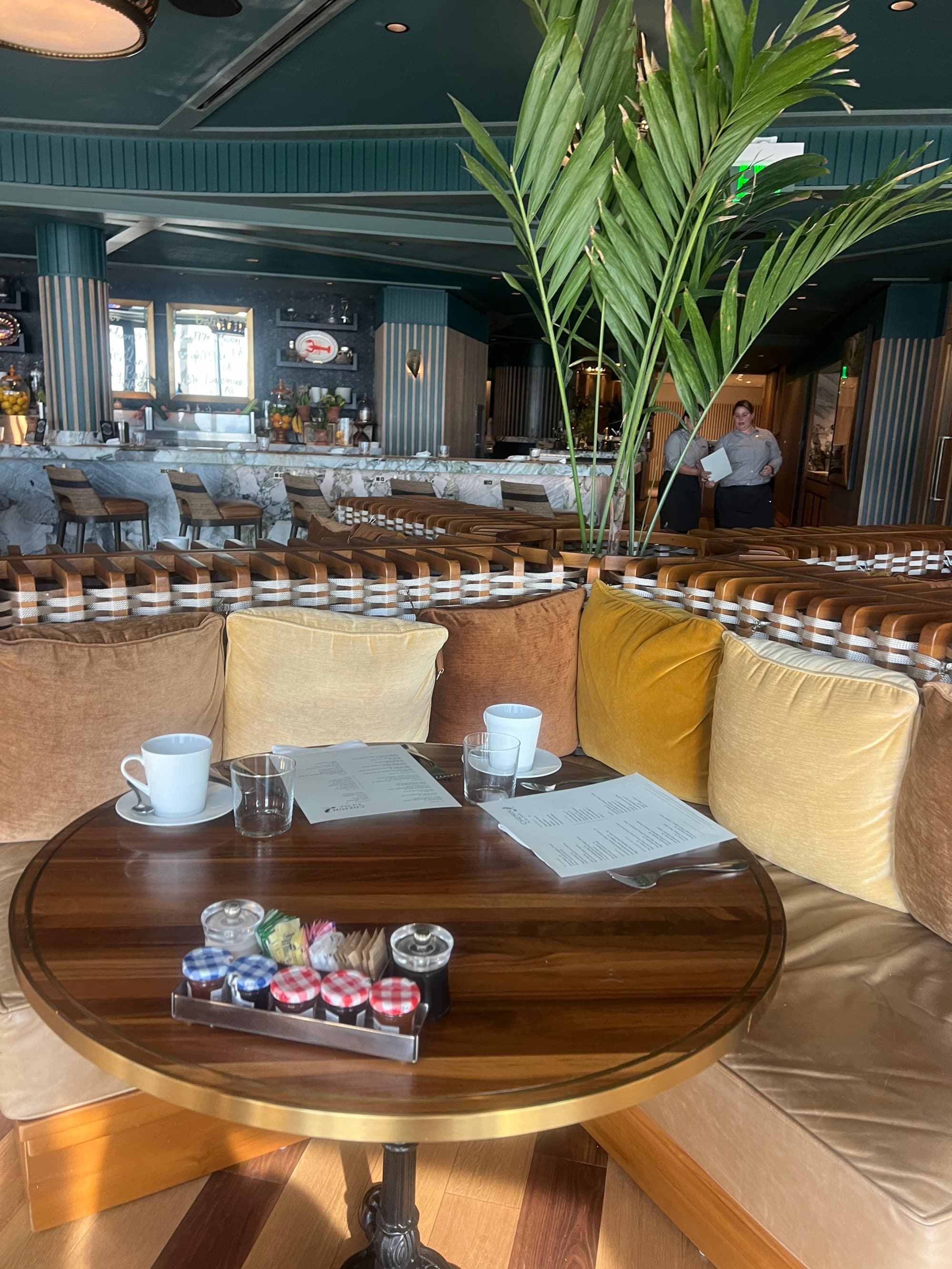 A view of a dining booth, the wooden table is topped with menus and coffee cups.