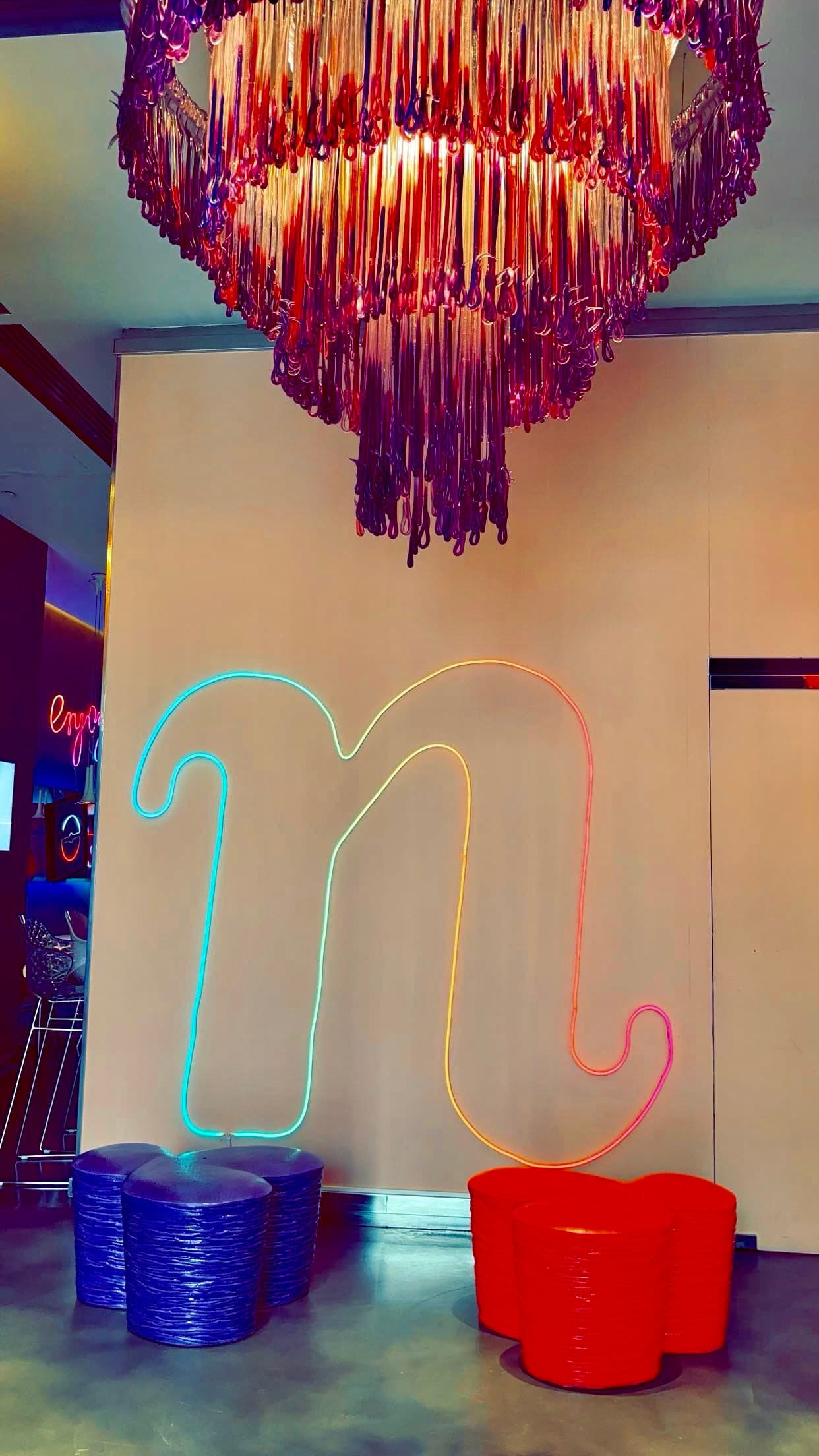 Purple chandelier hangs above small red and blue tables.